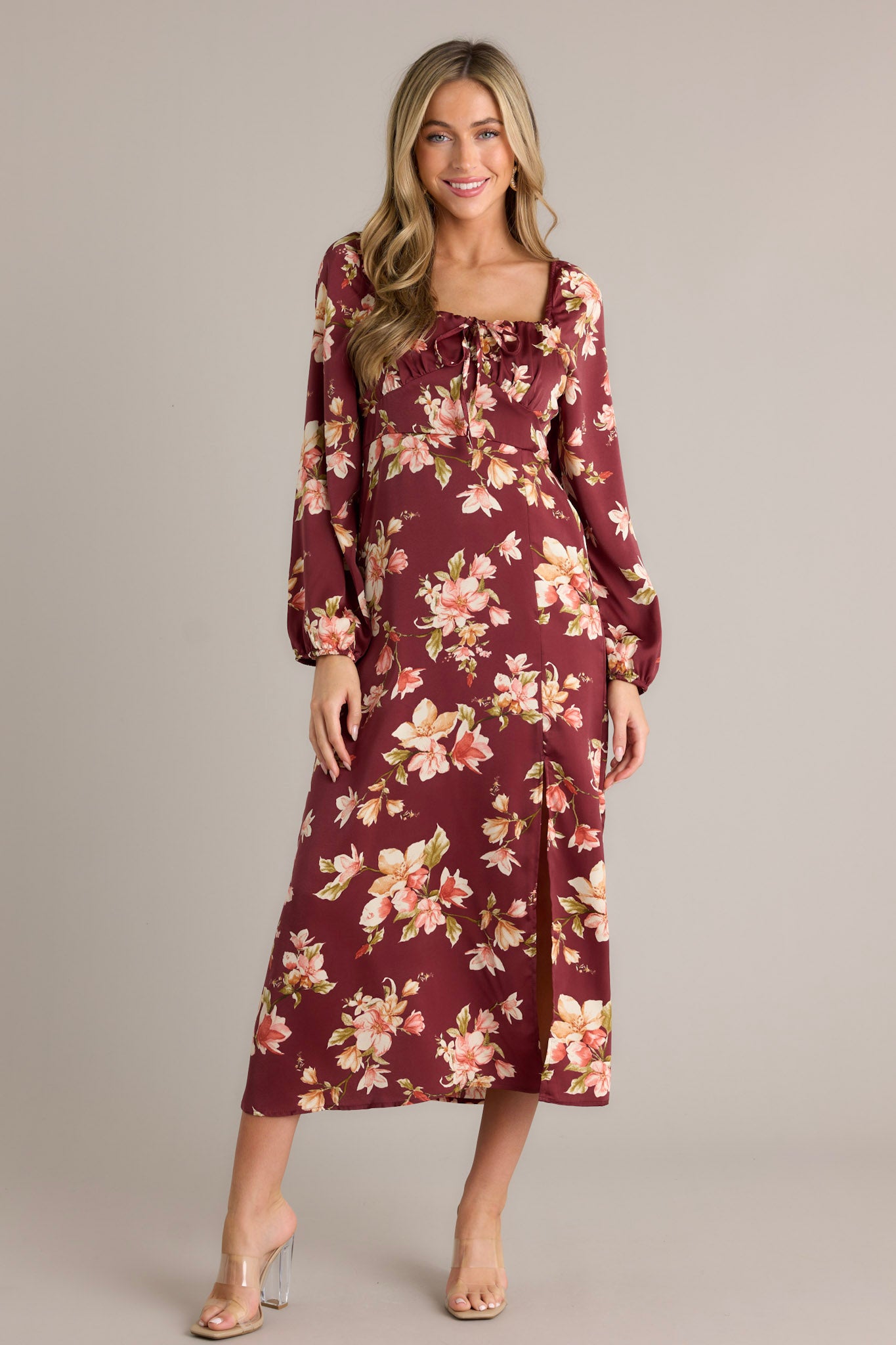 A burgundy dress with a floral print, featuring long sleeves, a square neckline, and a front slit, shown from the front.