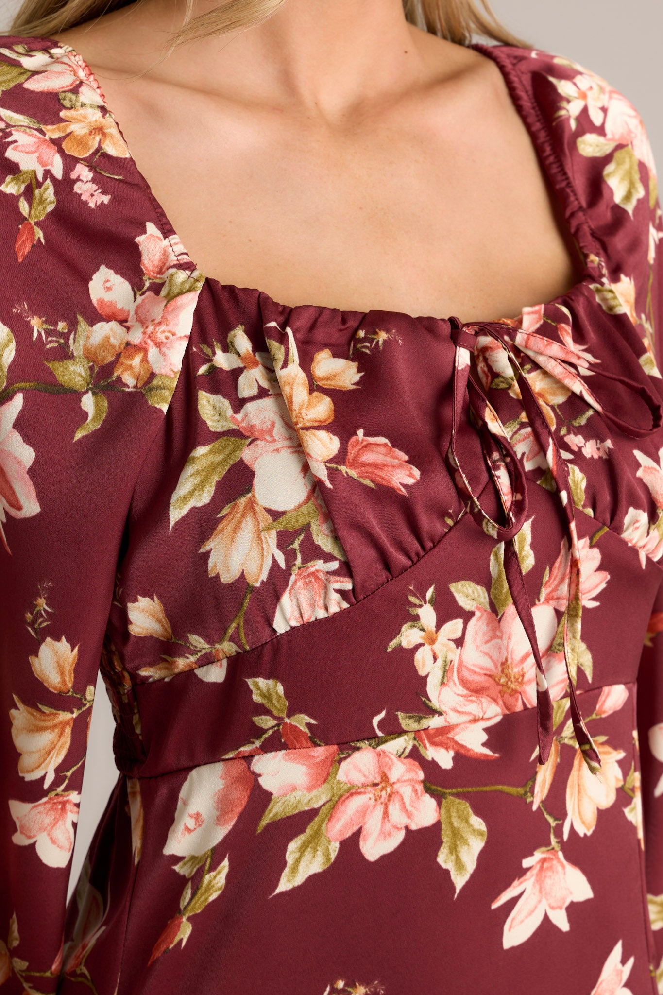 Close-up of the burgundy dress highlighting the square neckline, floral print, and tie detail.