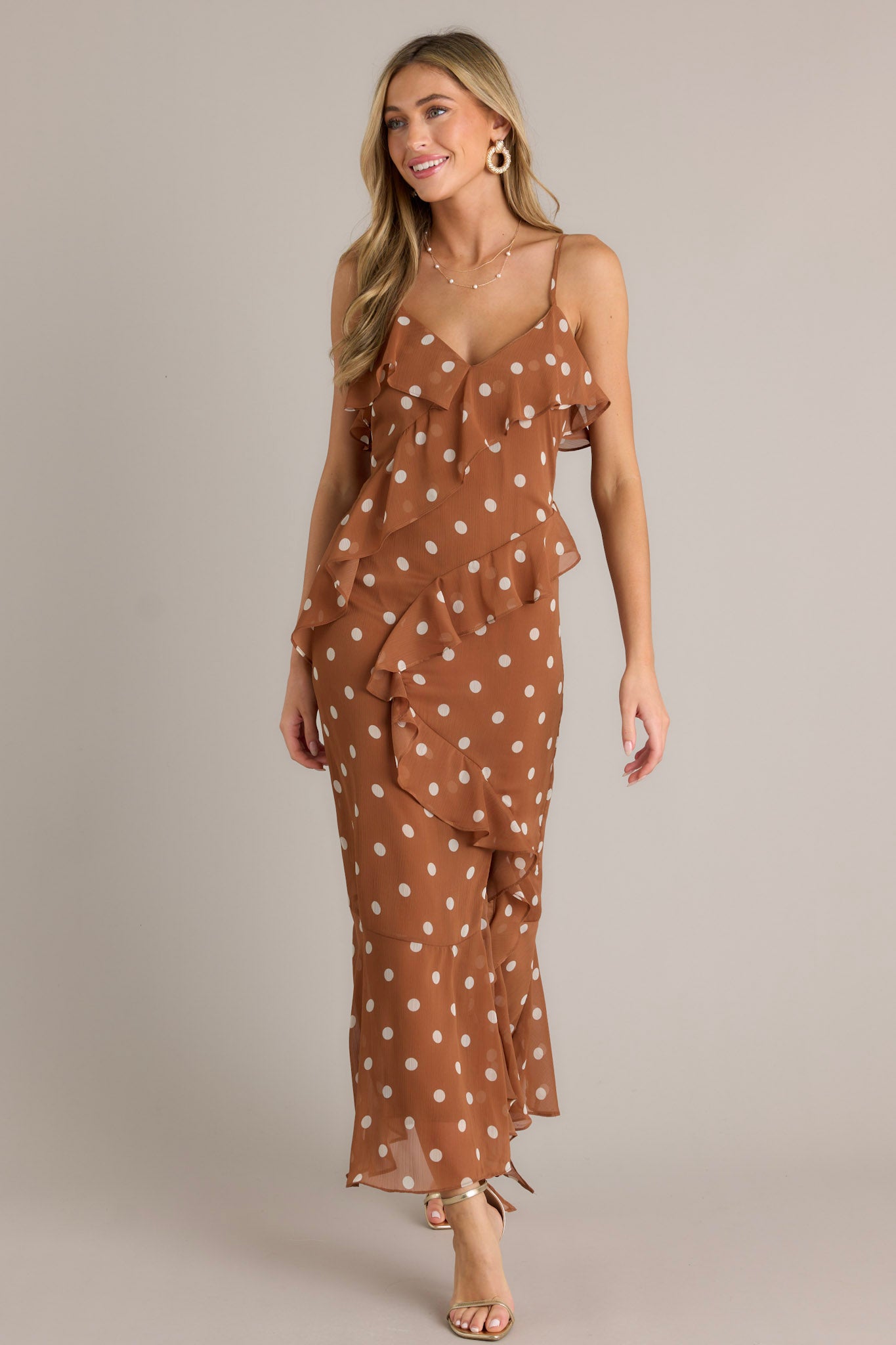 This brown dress features a v-neckline, ruffles throughout, an open leg slit, an self-tie leg ribbon, adjustable spaghetti straps and a flowing silhouette.