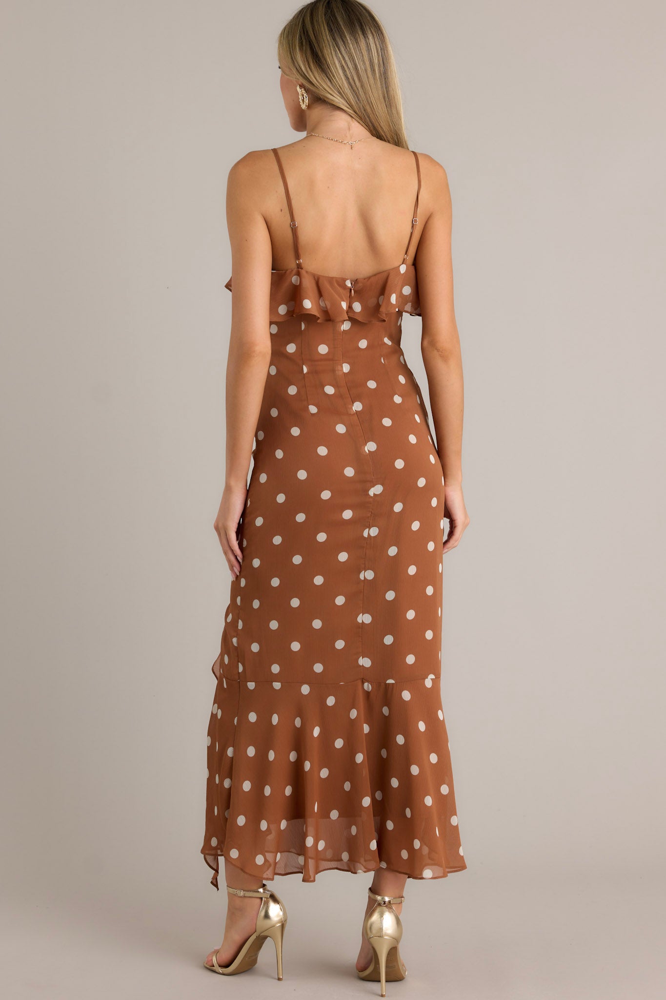 Back view of a brown dress highlighting the adjustable spaghetti straps, ruffles, and overall flowing silhouette.