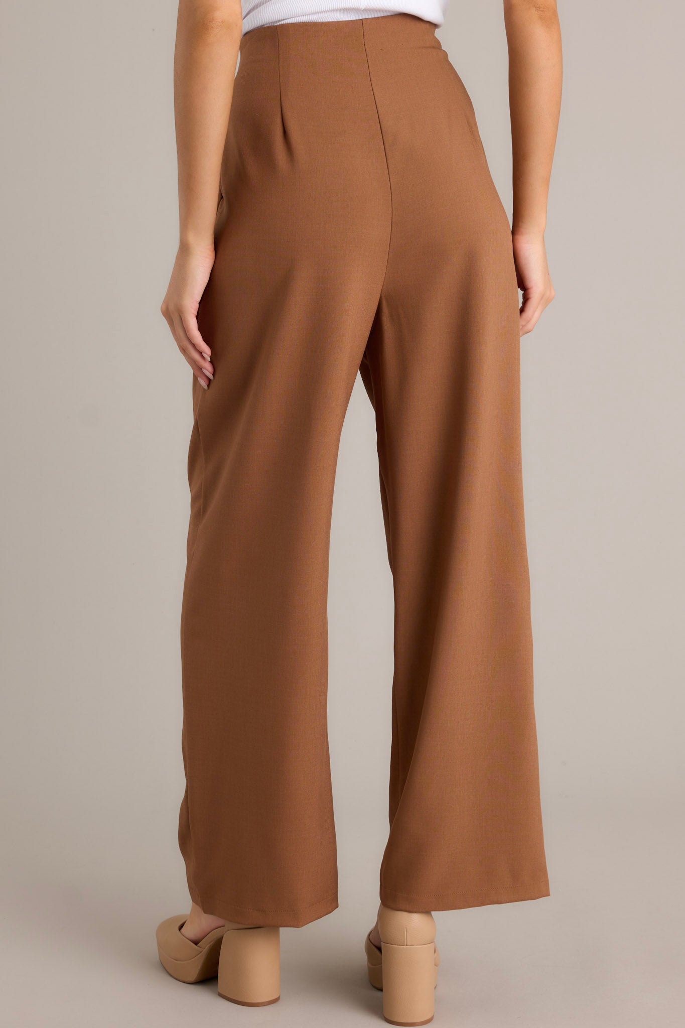 Back view of brown straight leg pants highlighting the high waisted design, straight leg cut, and back seam details.