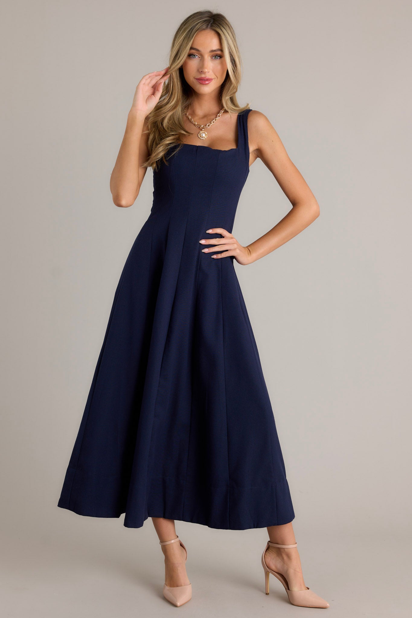 Full length view of a navy maxi dress with a square neckline, thick straps, a discrete back zipper, a flowing silhouette, and a thick hemline