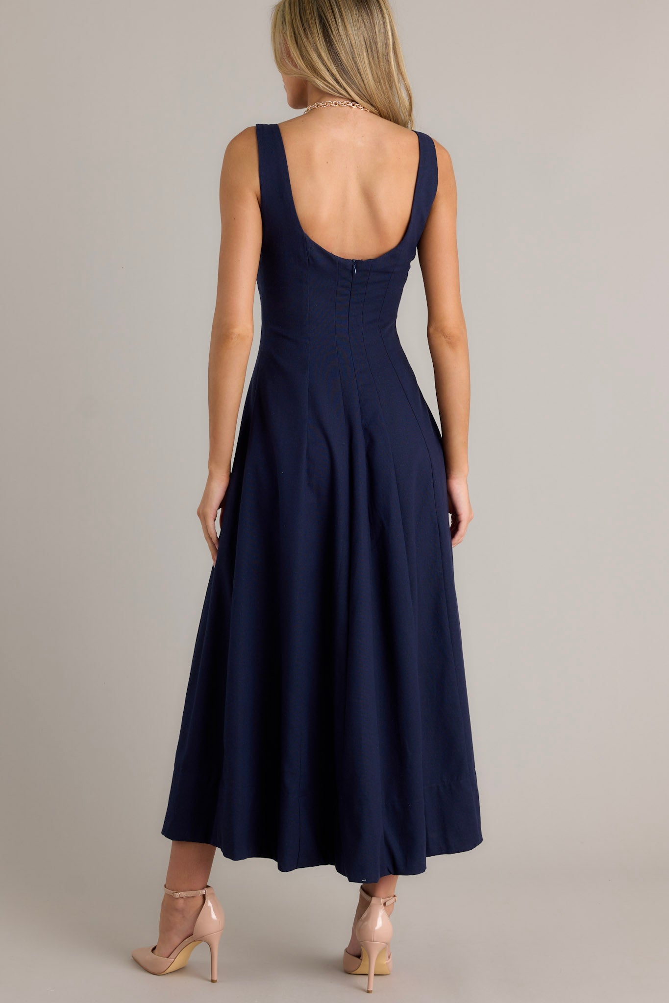 Back view of a navy maxi dress highlighting the discrete back zipper, thick straps, and the flowing silhouette.