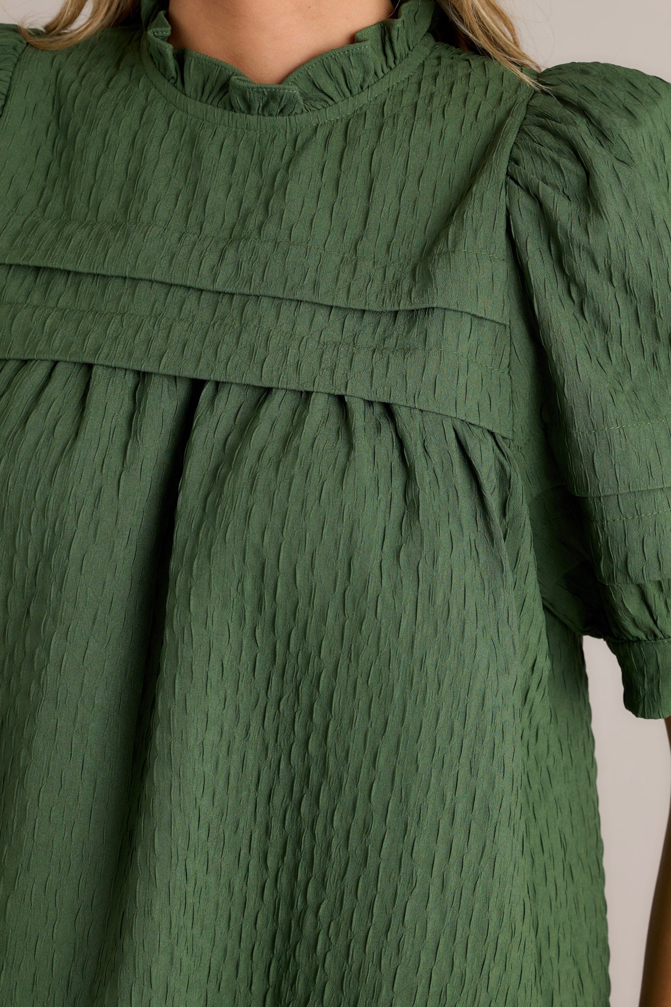 Close-up of the green top showing the high ruffled neckline, detailed seersucker texture, and the puff sleeves.