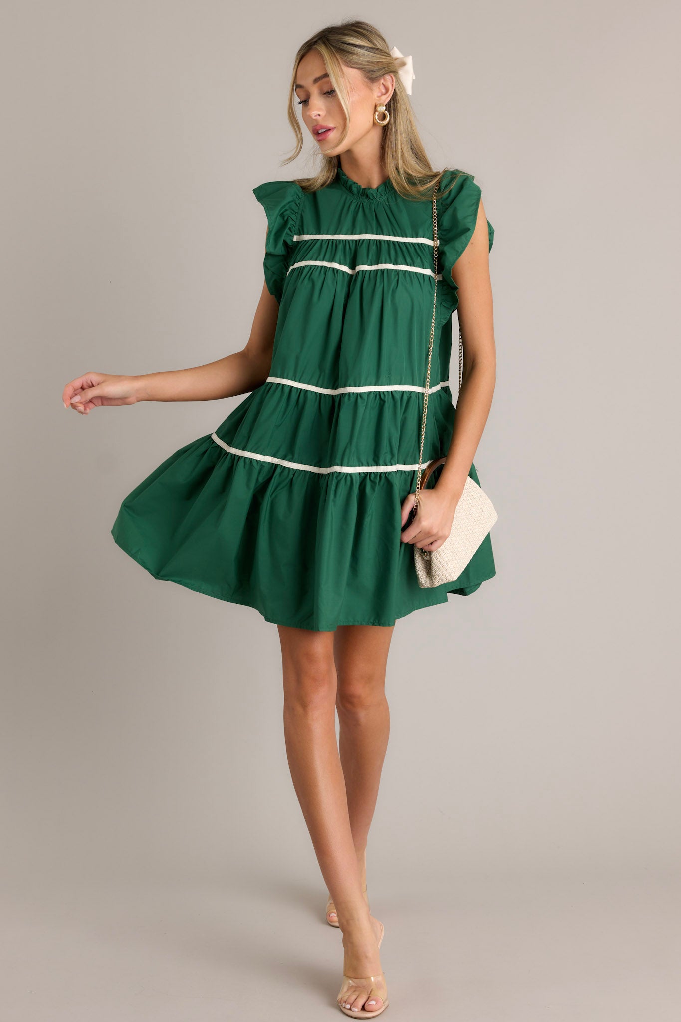 Action shot of a green dress displaying the flow and movement, highlighting the ruffled sleeves, round ruffle neckline, and functional pockets.