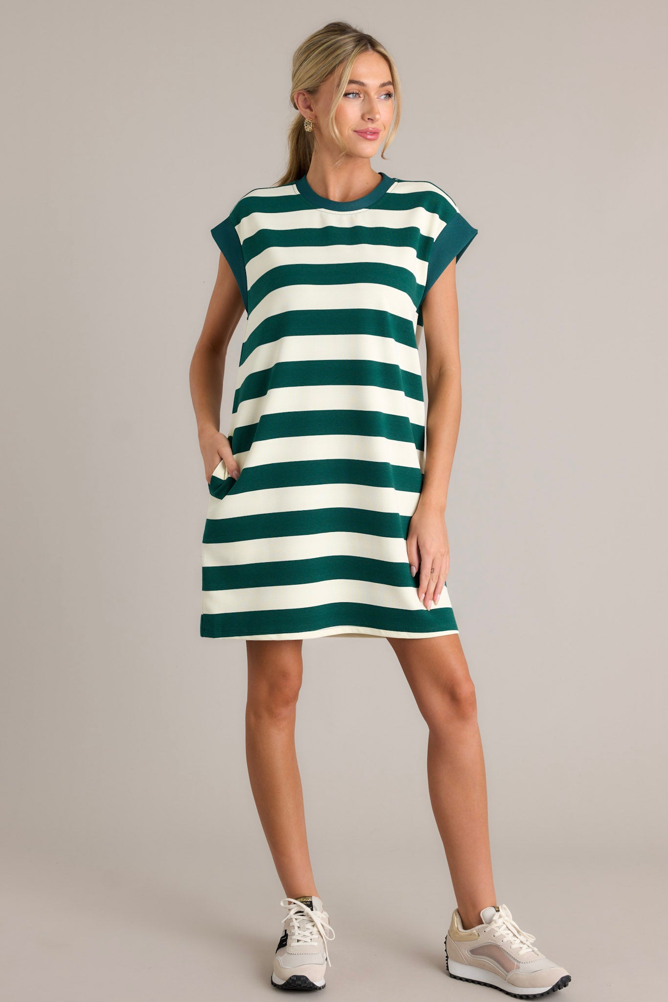 This forest green stripe mini dress features a crew neckline, wide cap sleeves, functional hip pockets, and a relaxed fit.