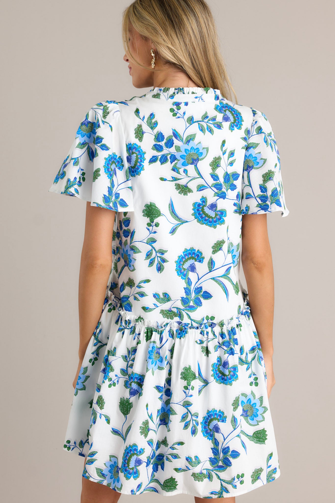 Back view of a blue floral dress highlighting the short sleeves and the flow of the single tier.