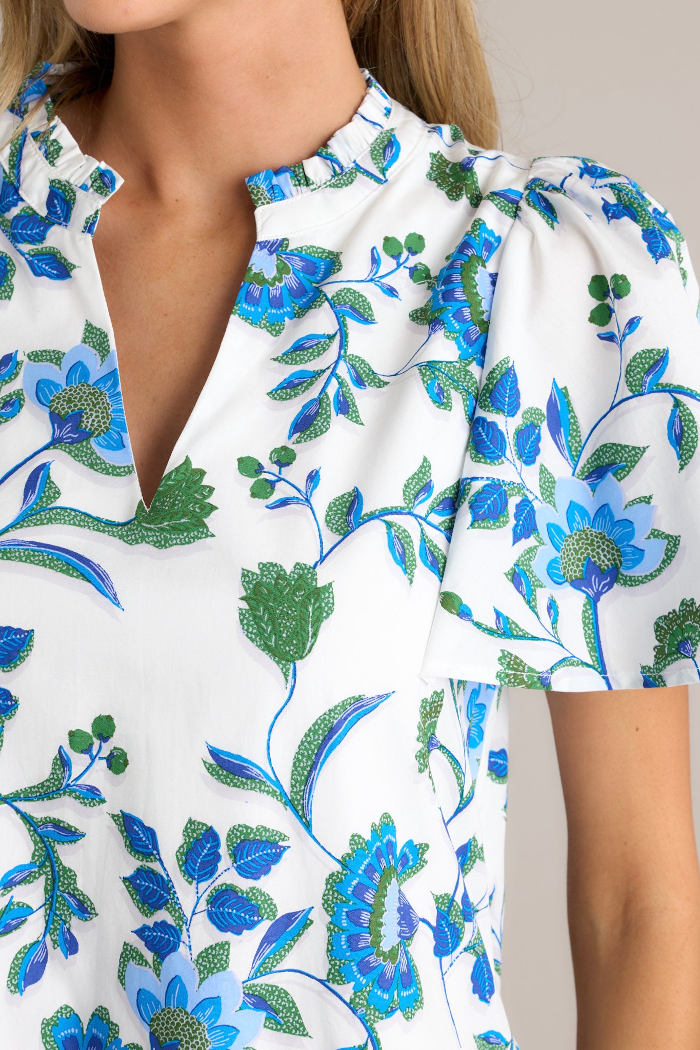 Close-up of a blue floral dress showing the pleated detailing around the v-neckline and the floral pattern.