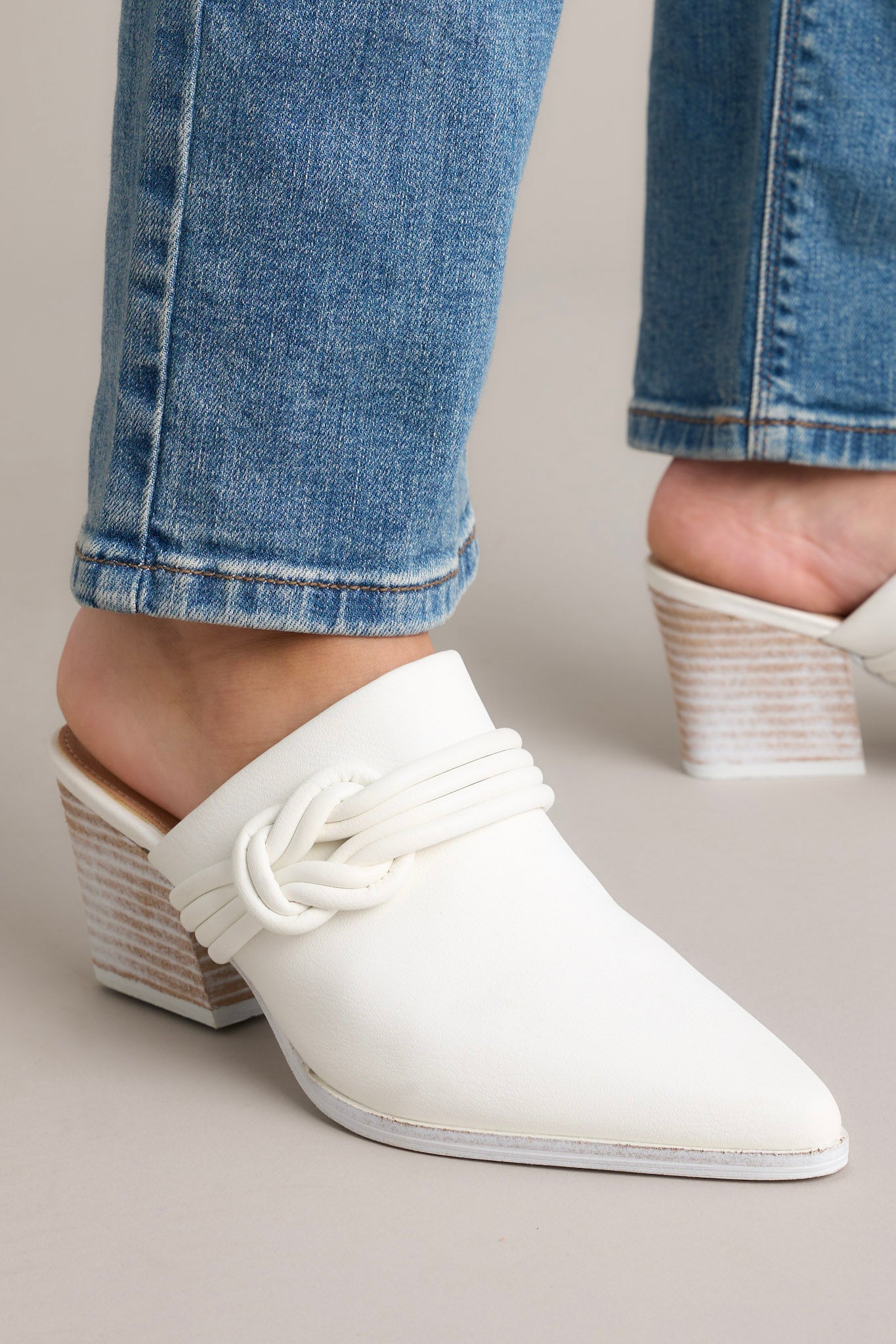 Front angled view of these shoes that feature a pointed toe, a braided detail across the top of the foot, a slip-on, open back design, and a block heel.