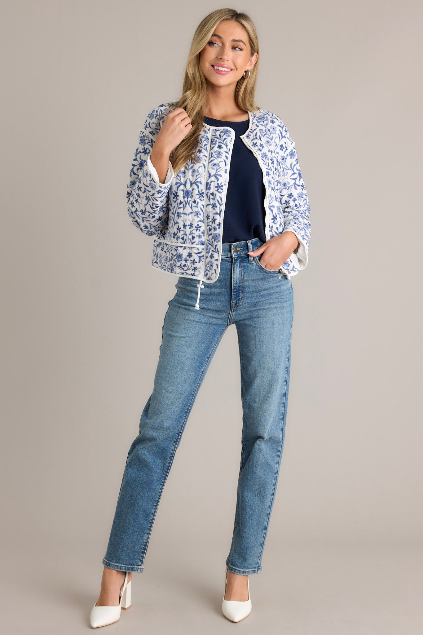 Front view of a blue jacket featuring a fun floral print, a round neckline, a hidden zipper, and front buttons.