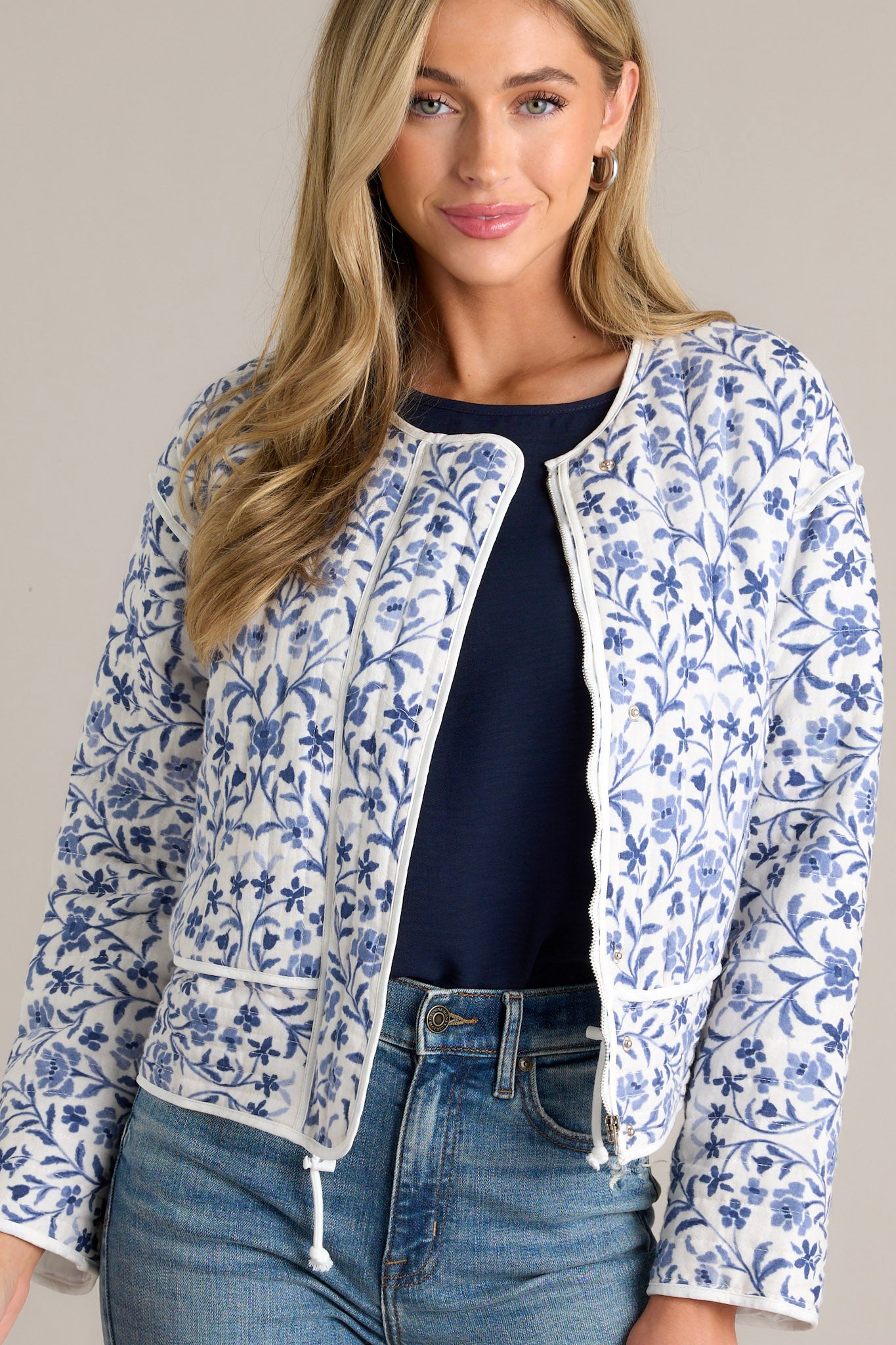 This blue jacket features a fun floral print, a round neckline, a hidden zipper, and front buttons.