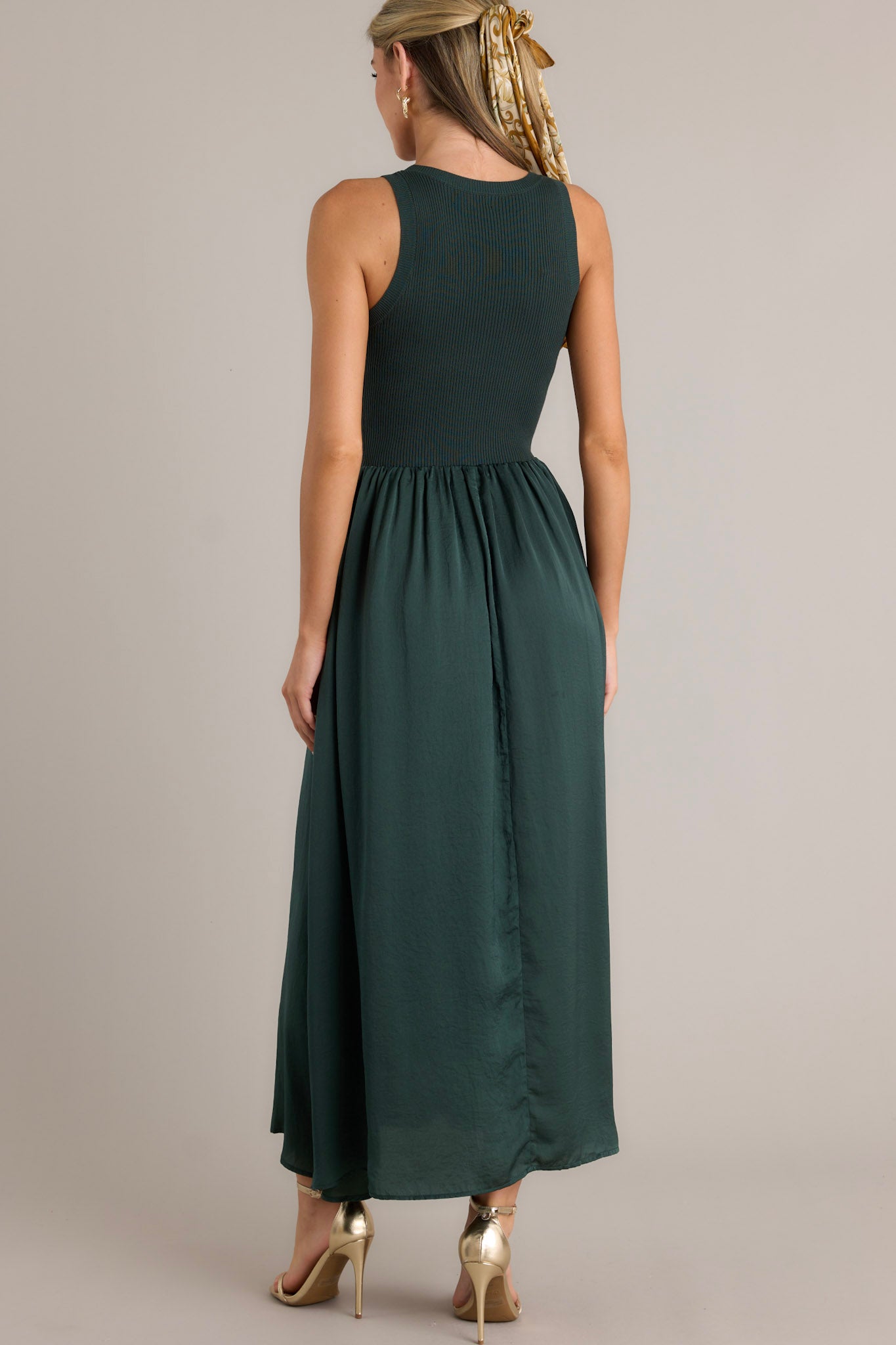 Back view of a sweater top dress highlighting the ribbed sweater bodice, the lightly pleated skirt, and the sleeveless design.