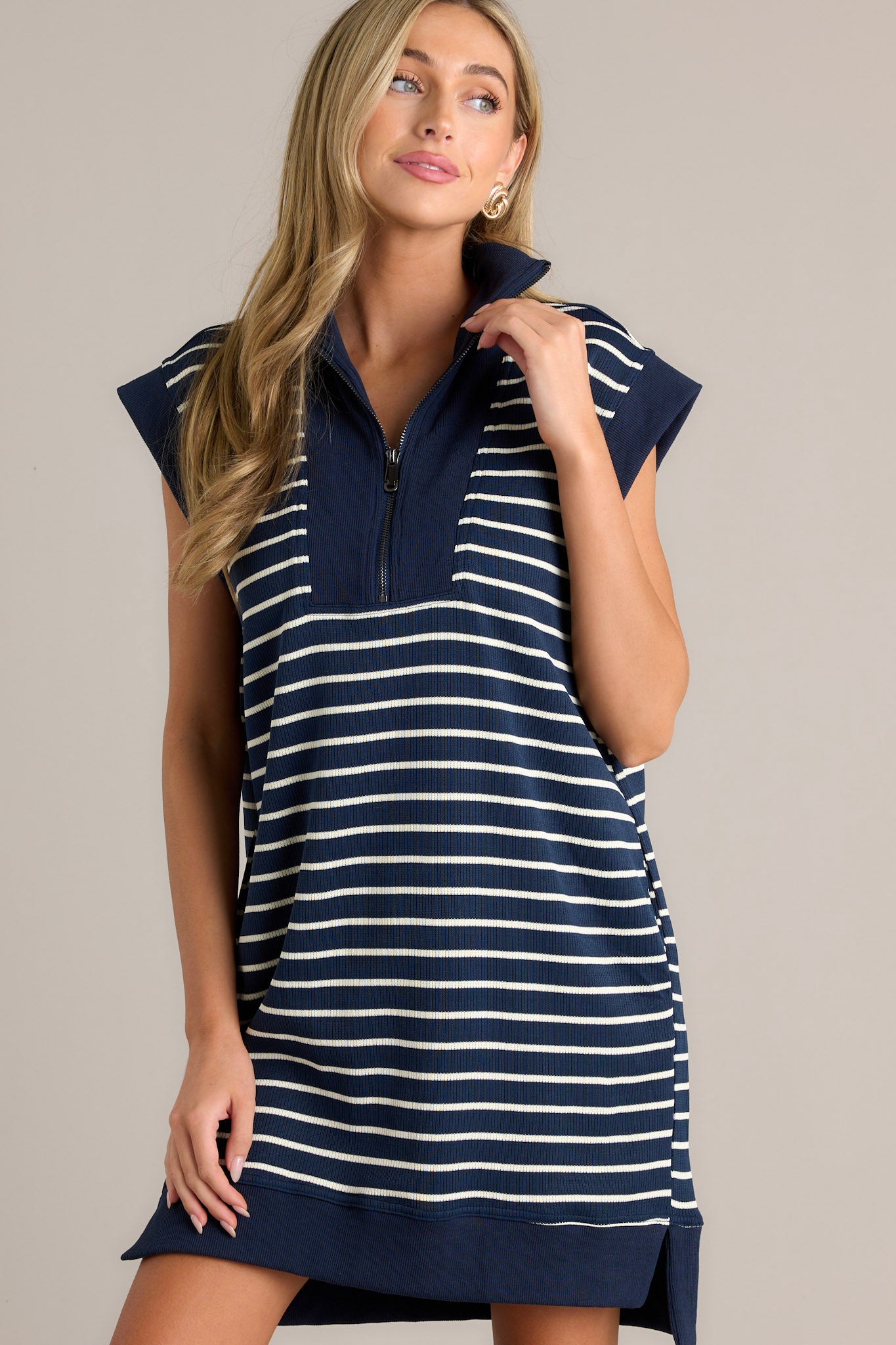 Trendy navy and white striped dress featuring a collared neck, quarter-zip, cap sleeves, and pockets.