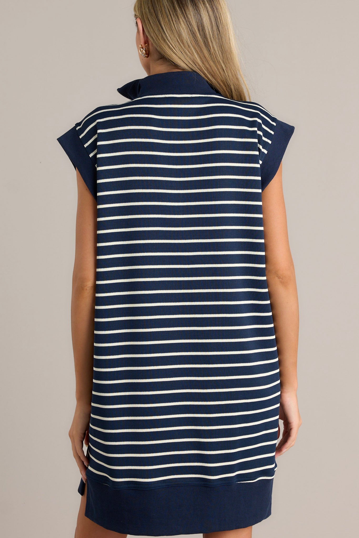 Back view of this navy and white striped dress  featuring a collared neck, quarter-zip, cap sleeves, and pockets.