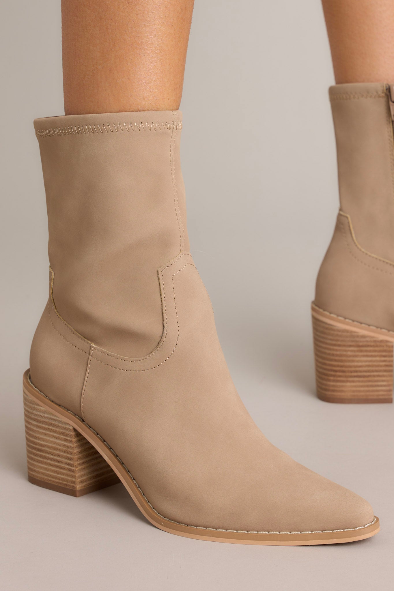 Close-up of these brown boots that feature a pointed toe, a platform heel, a discrete side zipper and a tan sole.