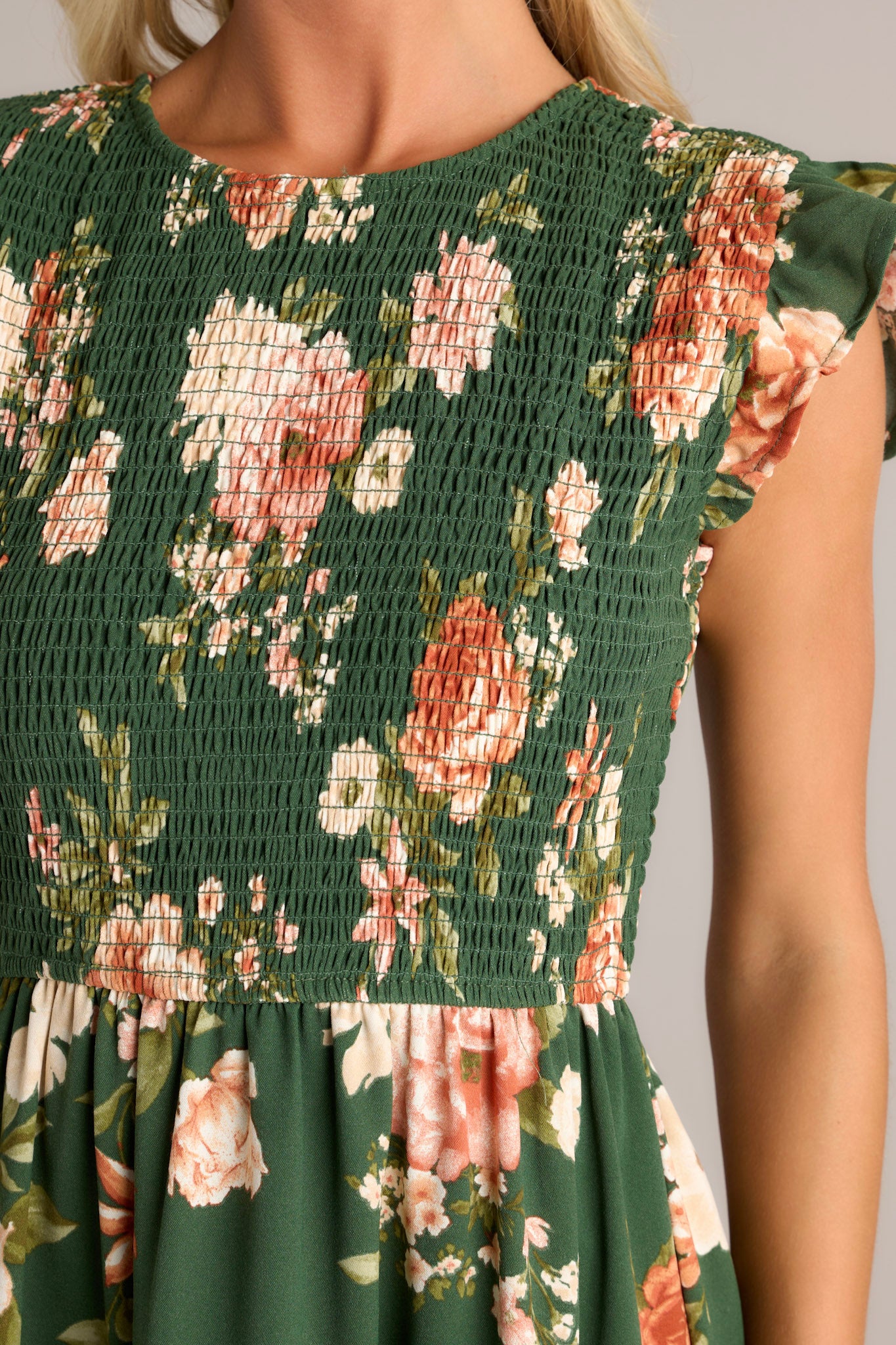 Close-up of the green dress showing the high neckline, fully smocked bodice, short ruffle sleeves, and tiered design.