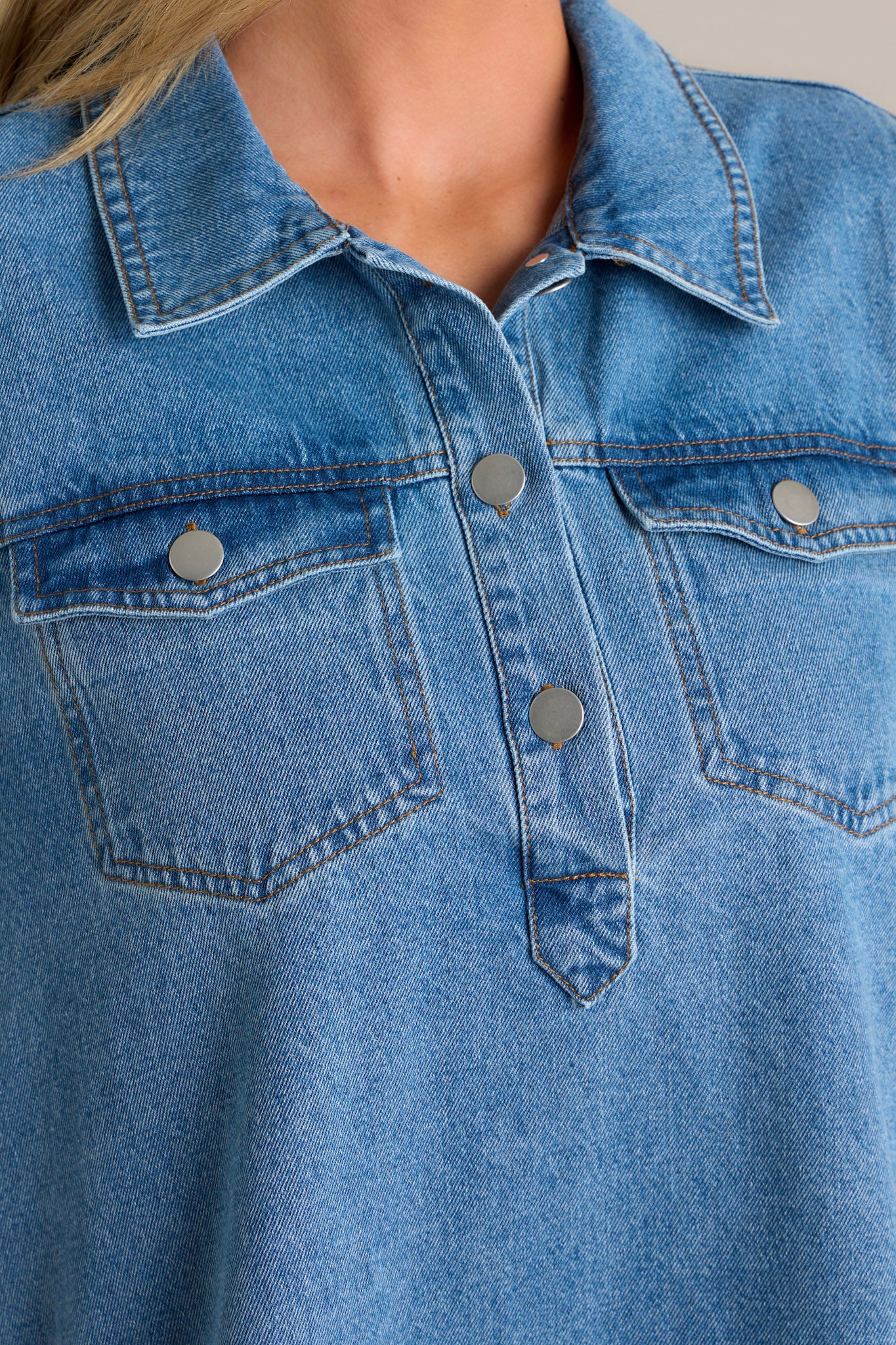 Close-up of the denim mini dress focusing on the collared neckline, functional button front bust, button-closure bust pockets, and the sturdy denim fabric