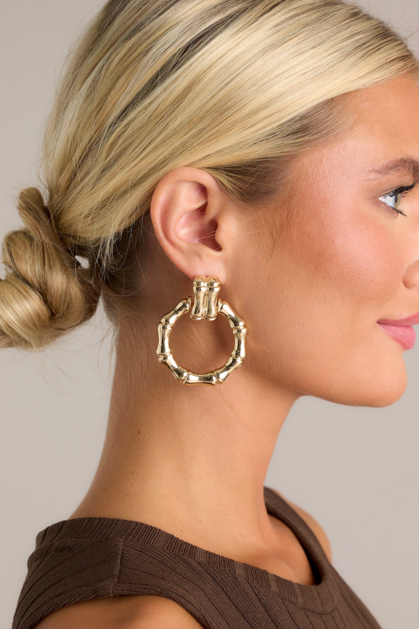 Close-up of these gold earrings that feature textured gold hardware, a textured stud with a connected textured hoop, and secure post backings.