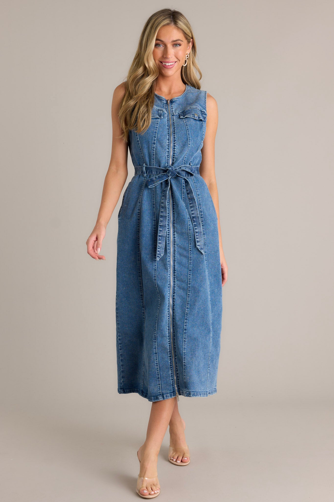 Action shot of the denim dress displaying the flow and movement of the fabric, highlighting the functional front zipper, self-tie denim drawstring belt, and sleeveless design.