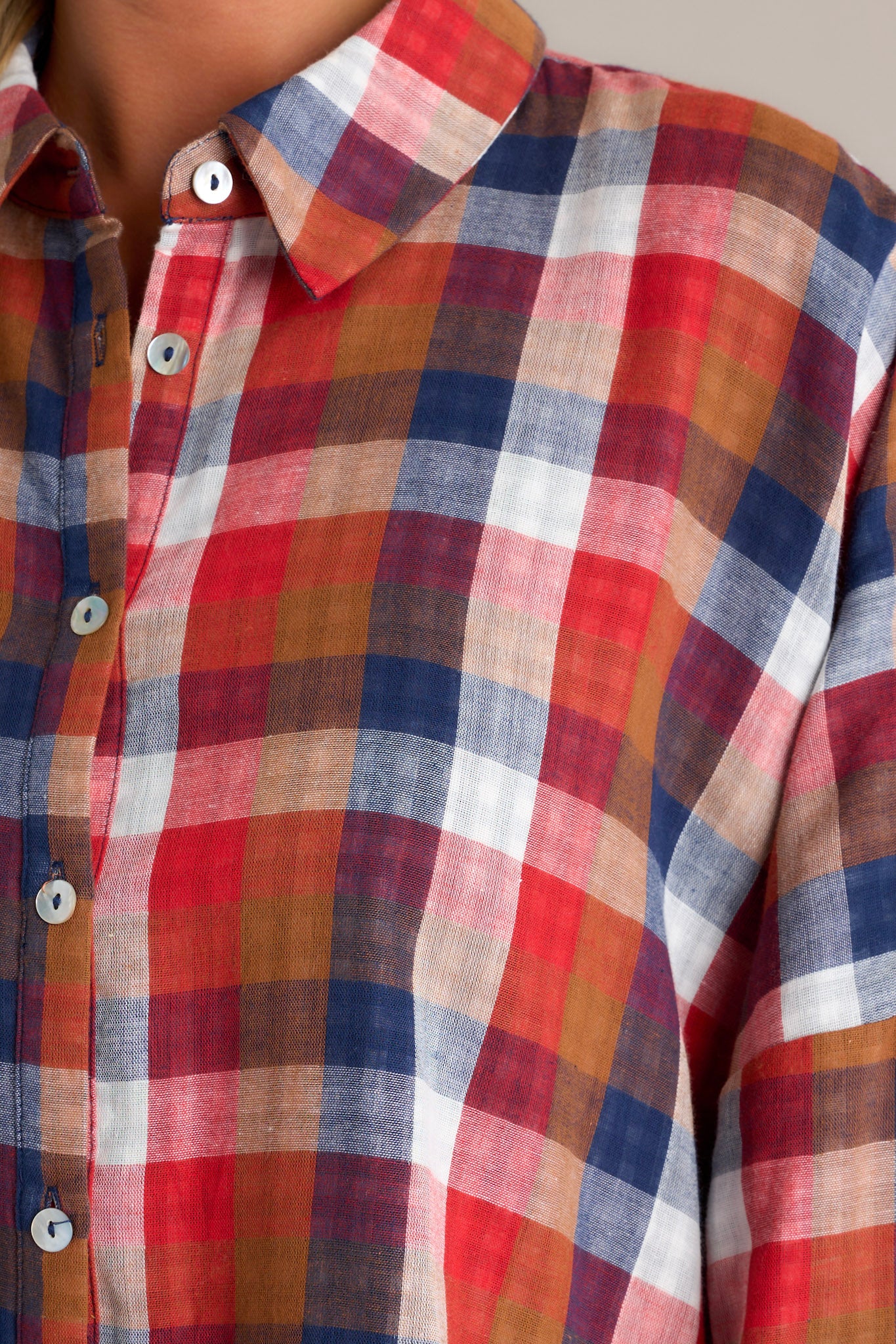 Close-up of the top focusing on the collared neckline, the functional buttons down the front, and the contrasting interior print visible from the cuffed sleeves.