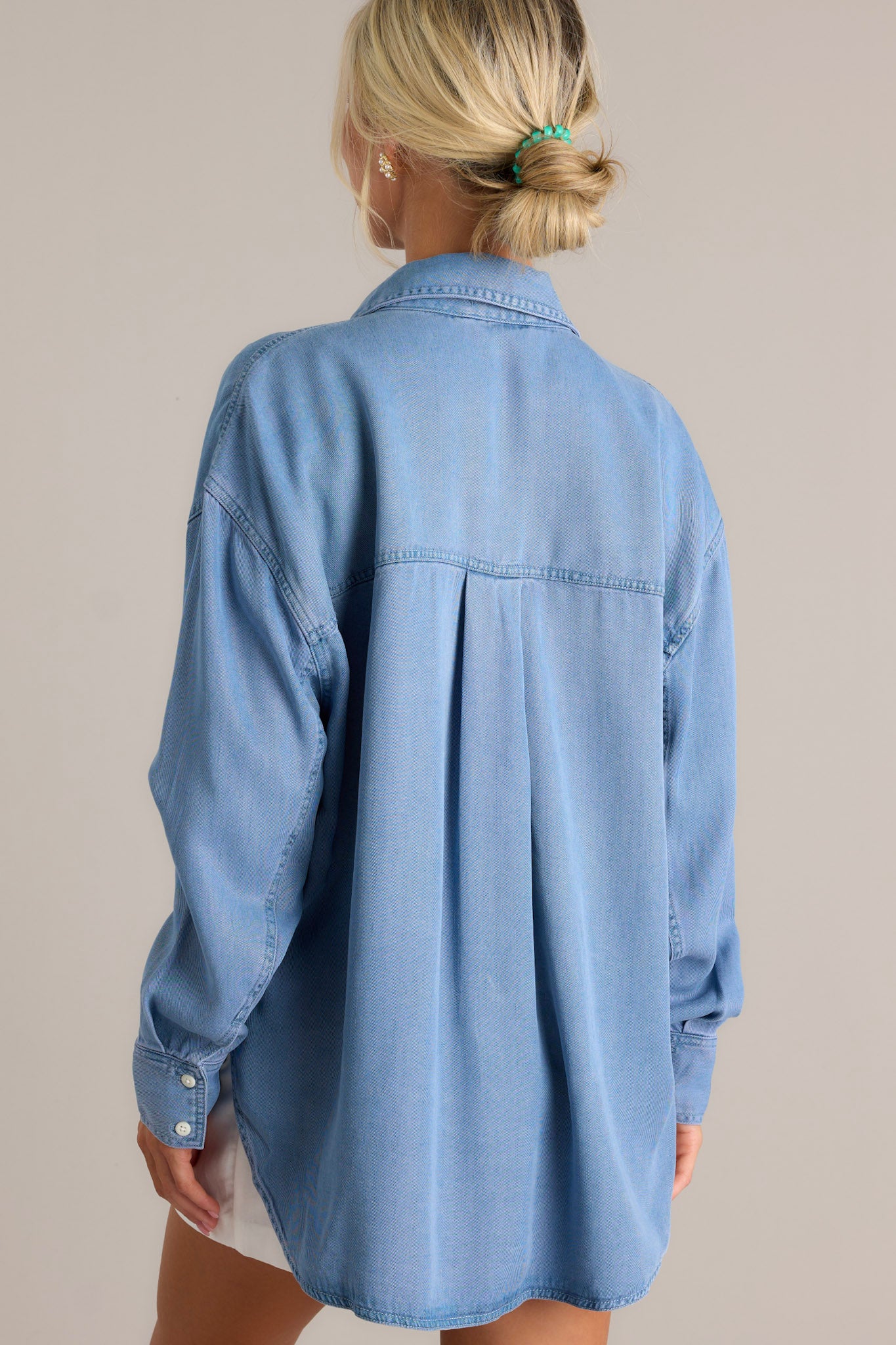 Back view of the chambray top highlighting the drop cut style and the fit of the long sleeves.