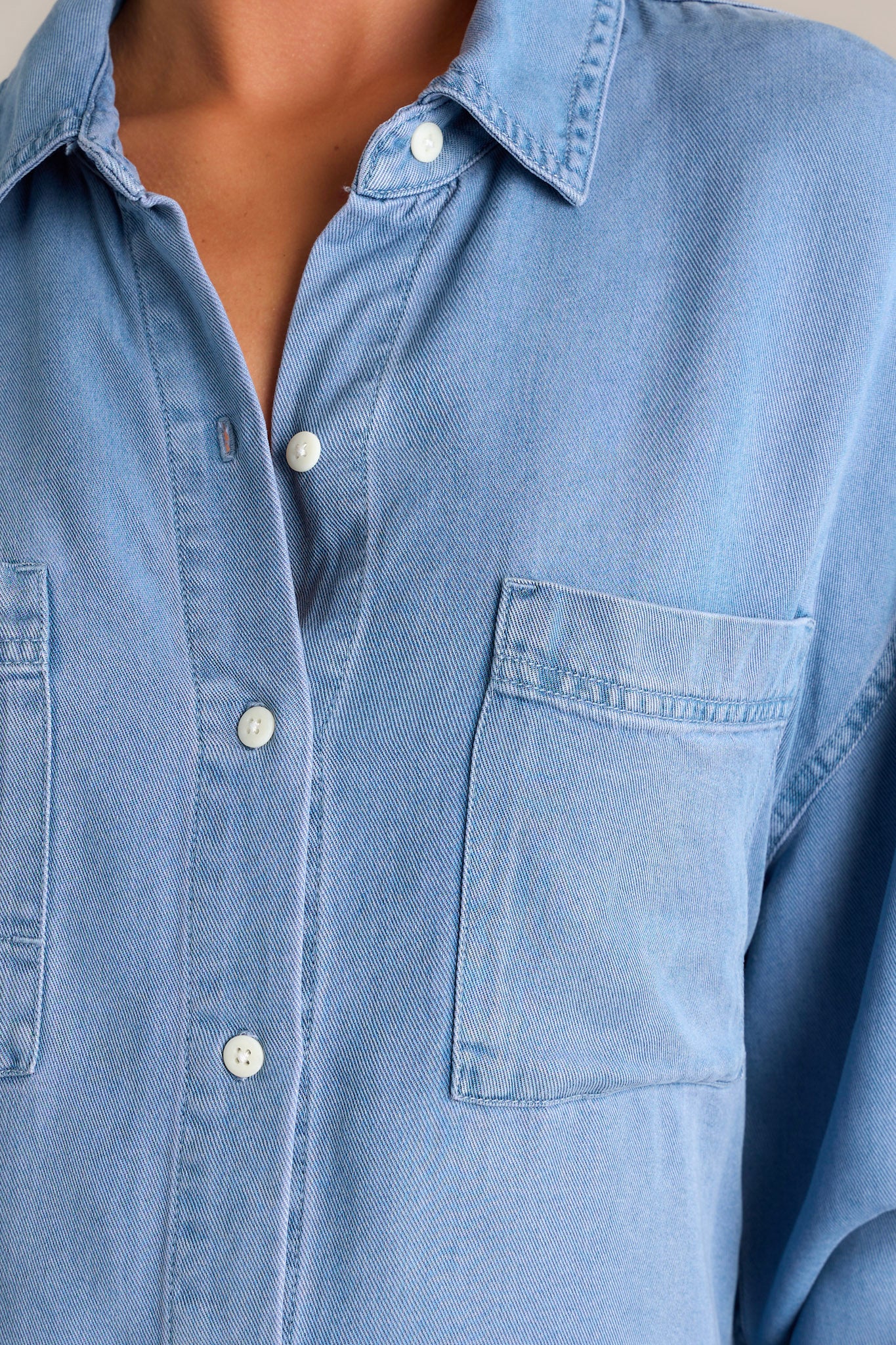 Close-up of the chambray top focusing on the collared neckline, functional button front, and the details of the chest pockets.