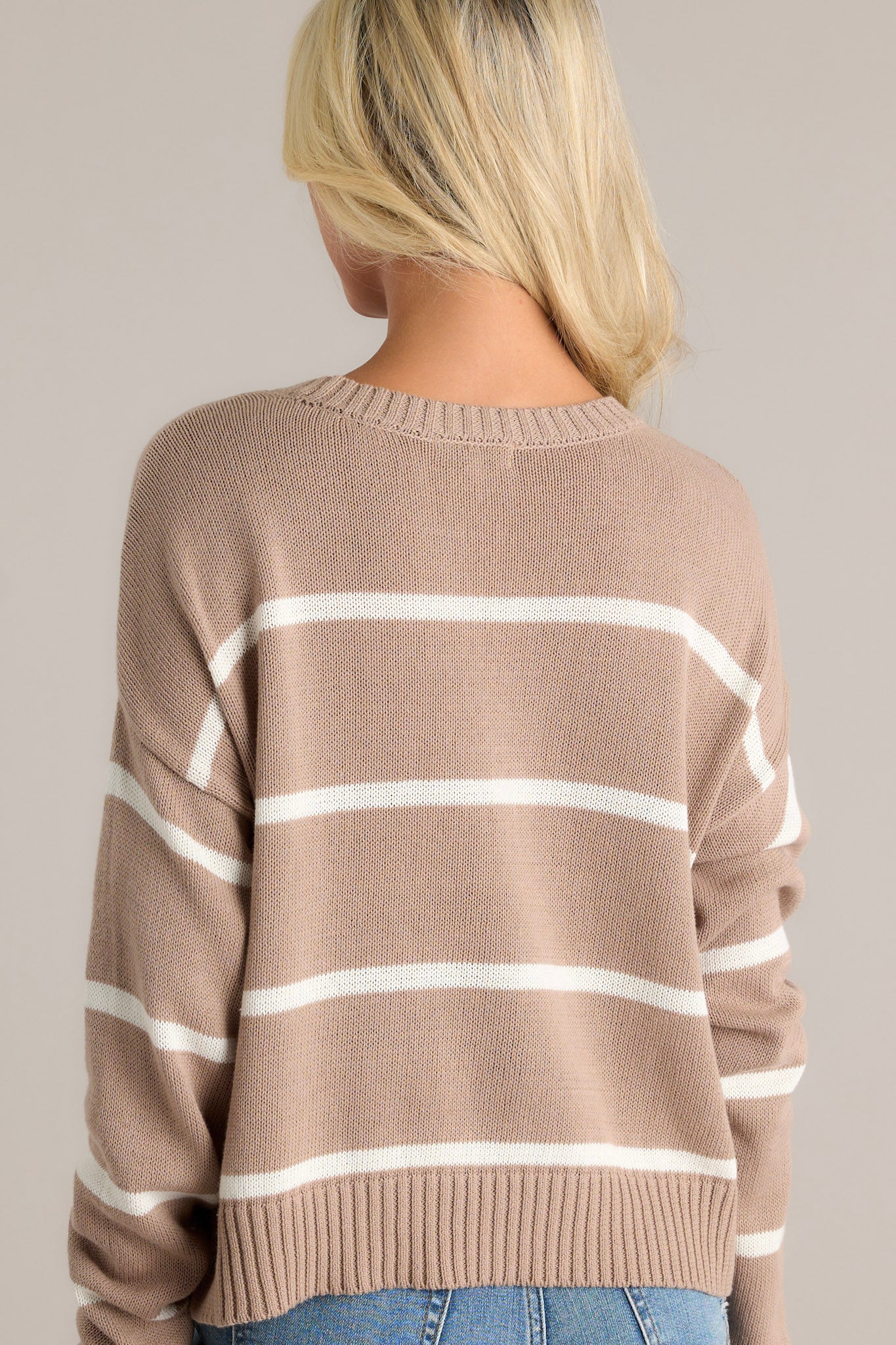 Back view of the latte tan stripe sweater showcasing ribbed hems and stripe pattern.