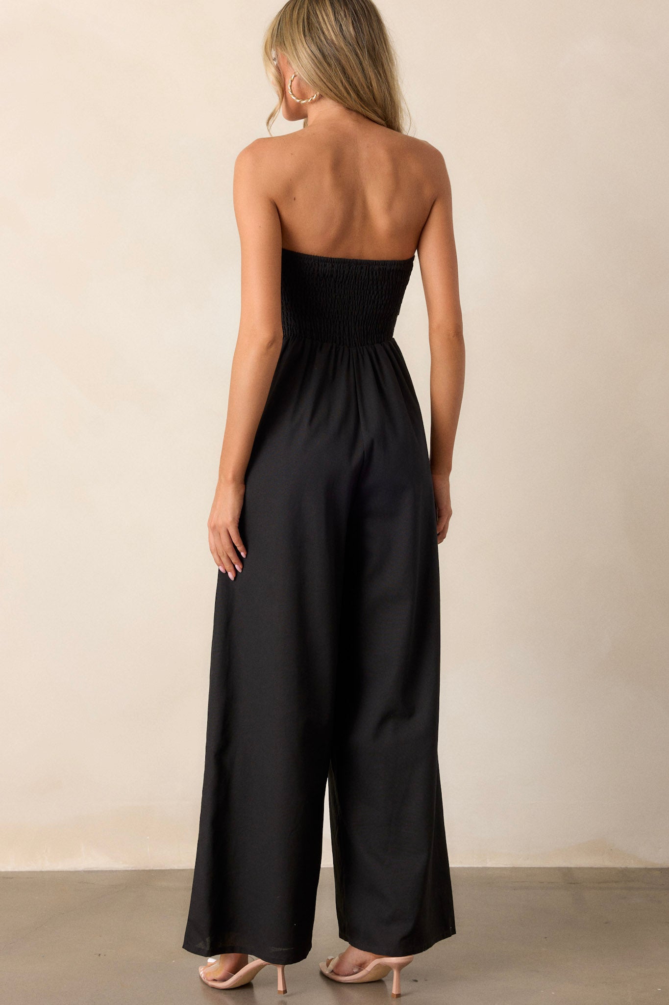 Back view of the jumpsuit highlighting the smocked back and the flow of the wide leg bottoms.