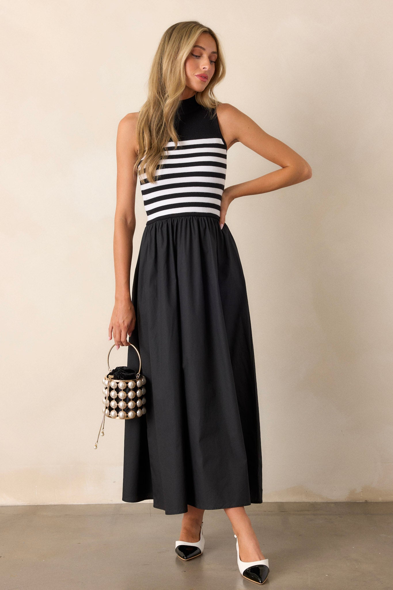 Full length view of a black stripe maxi dress featuring a high neckline, a striped sweater bodice, and a flowy skirt