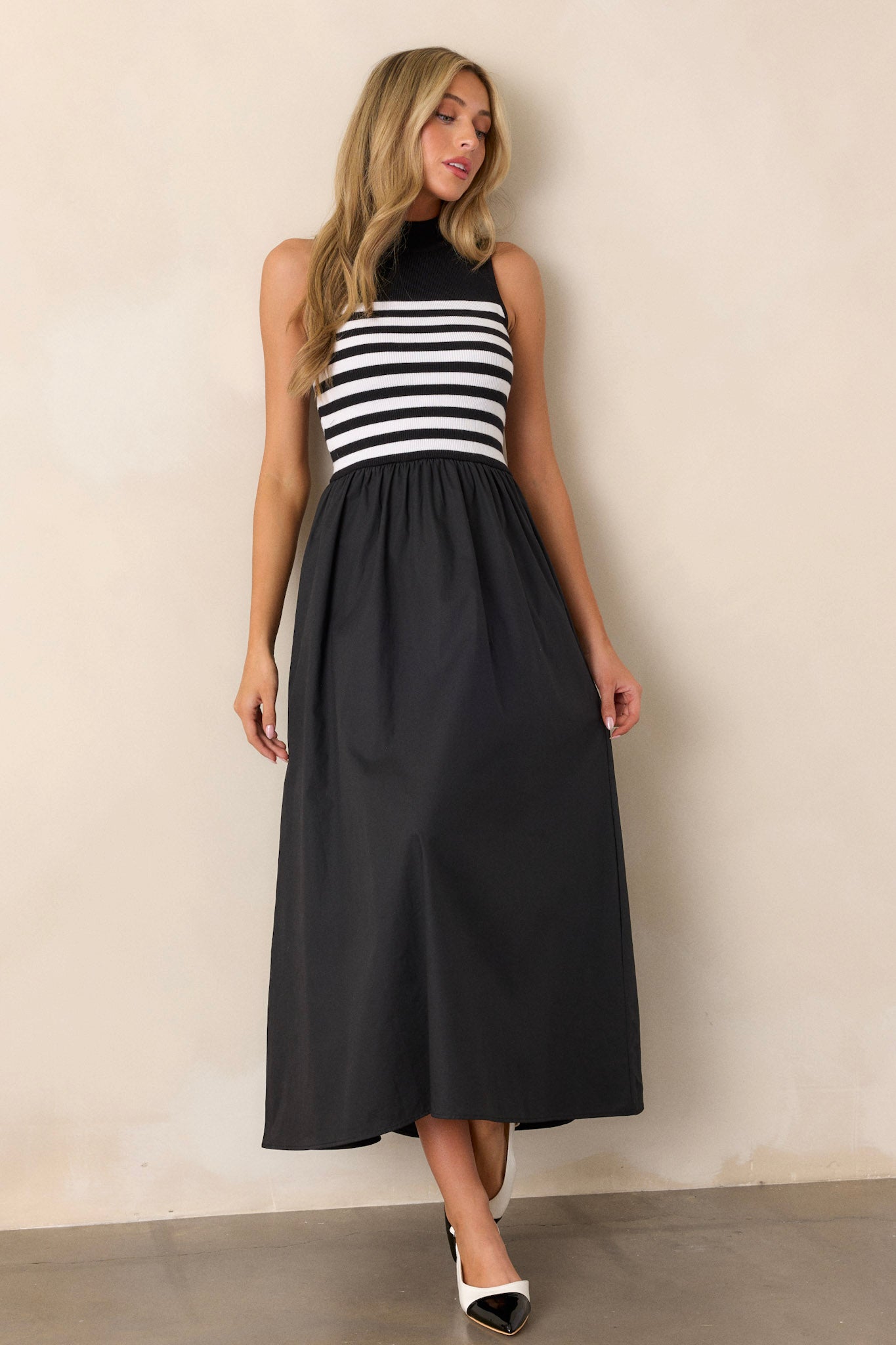 Action shot of the black stripe maxi dress displaying the movement and flow of the skirt, with the high neckline and striped sweater bodice in view.