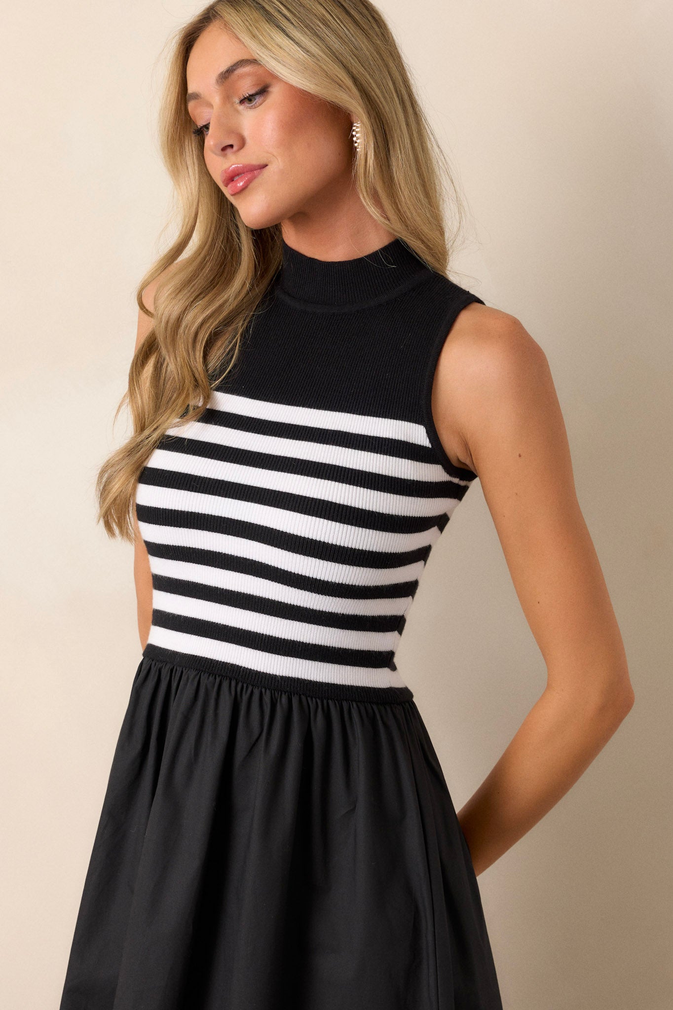 Front angled view of a black stripe maxi dress featuring a high neckline, a striped sweater bodice, and a flowy skirt