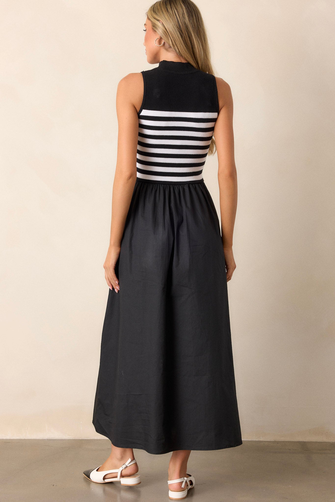 Back view of the black stripe maxi dress highlighting the flowy skirt and the continuity of the striped sweater bodice.