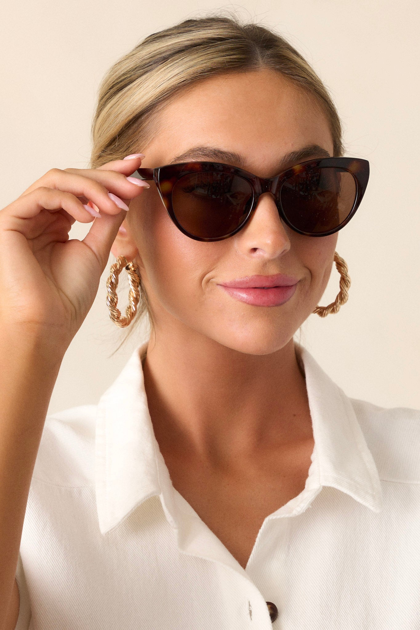 These brown sunglasses feature a rounded cat eye shape, a brown frame, thin arms and a solid color lens.