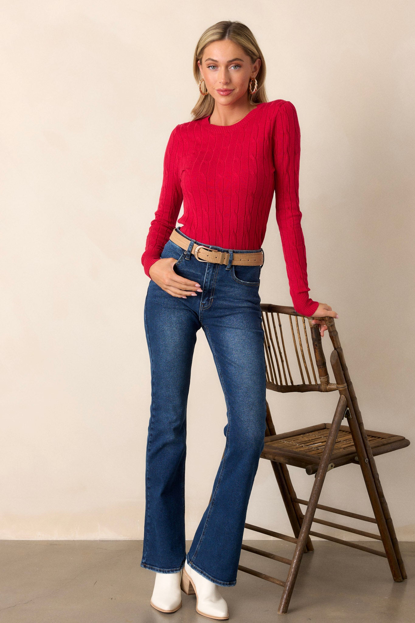 Full length view of the top featuring a cable knit design, ribbed wrists, and a ribbed neckline