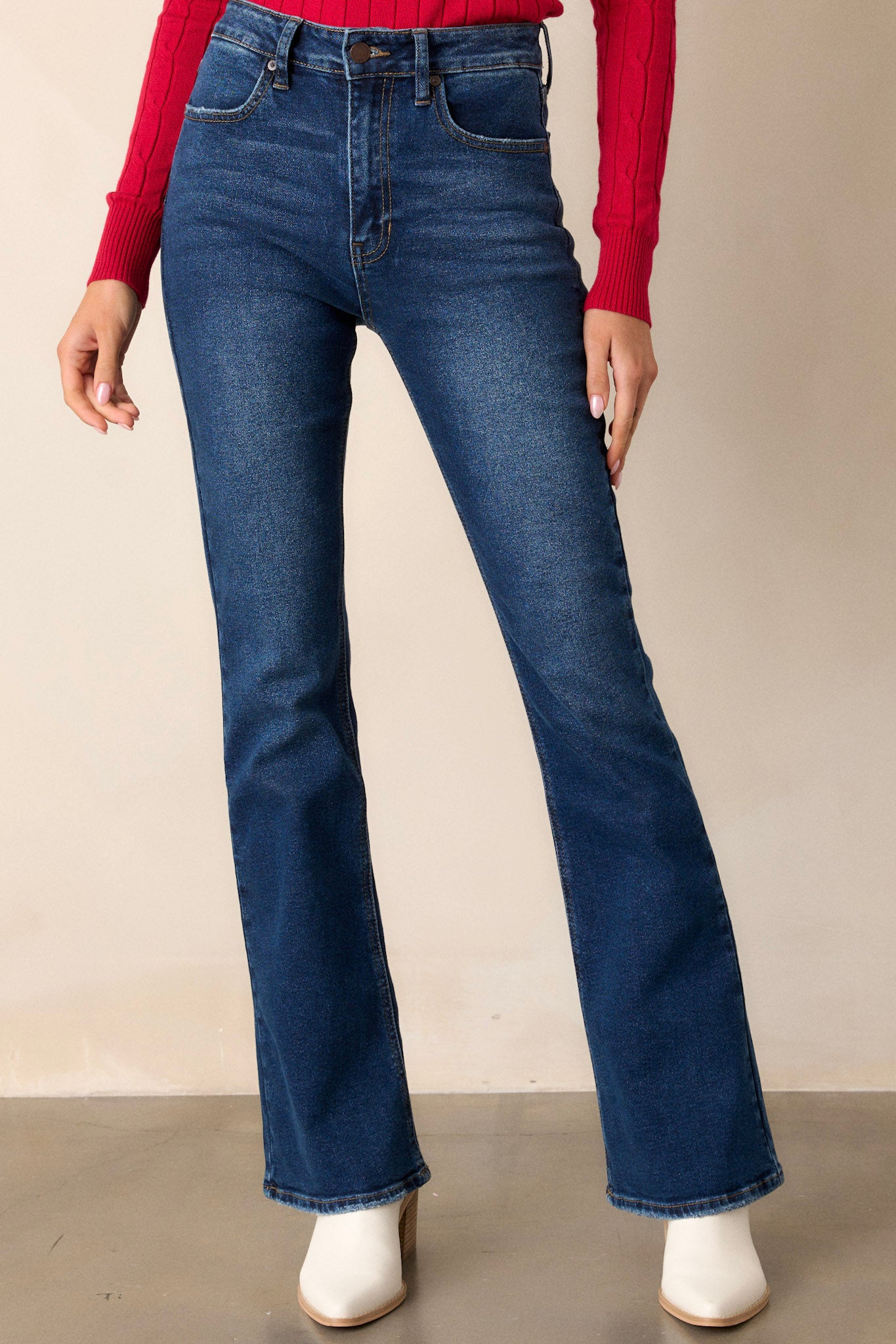 Front view of jeans featuring a high waisted fit, functional pockets on the front and back, belt loops, a zipper and button closure, and a flared out style.