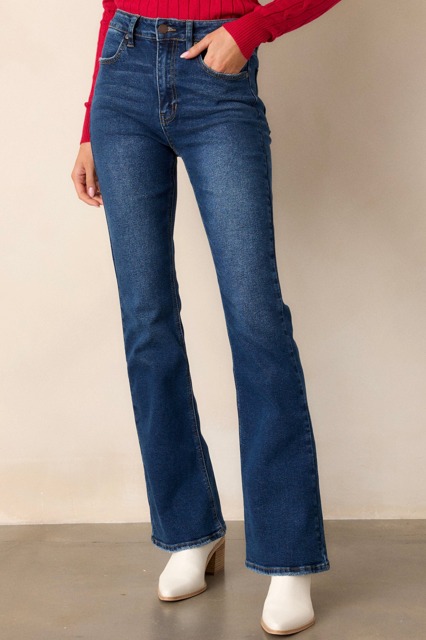 Angled front view of jeans featuring a high waisted fit, functional pockets on the front and back, belt loops, a zipper and button closure, and a flared out style.