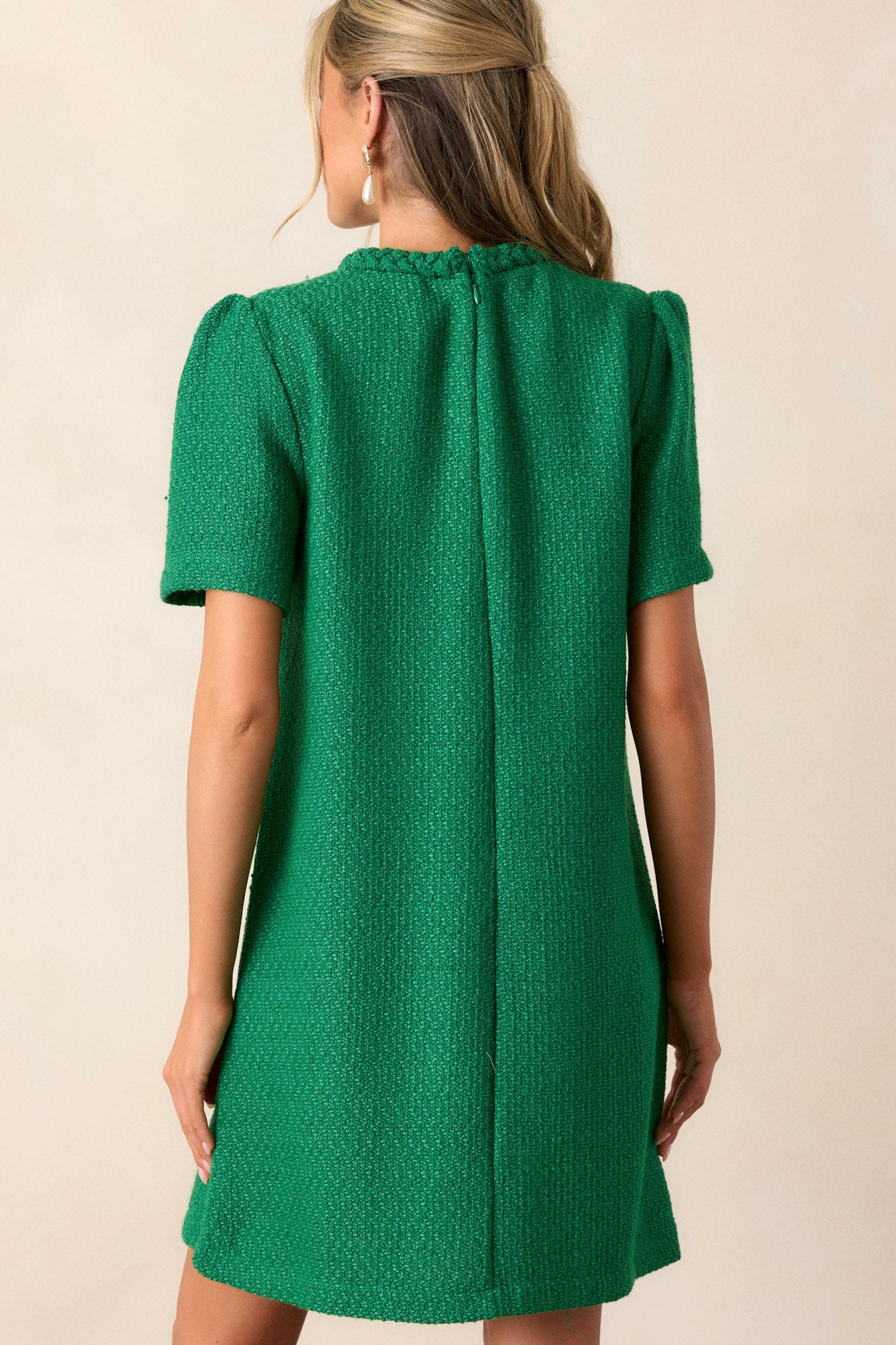 Back view of the green mini dress showcasing the discrete back zipper, the braided round neckline, and the tweed material