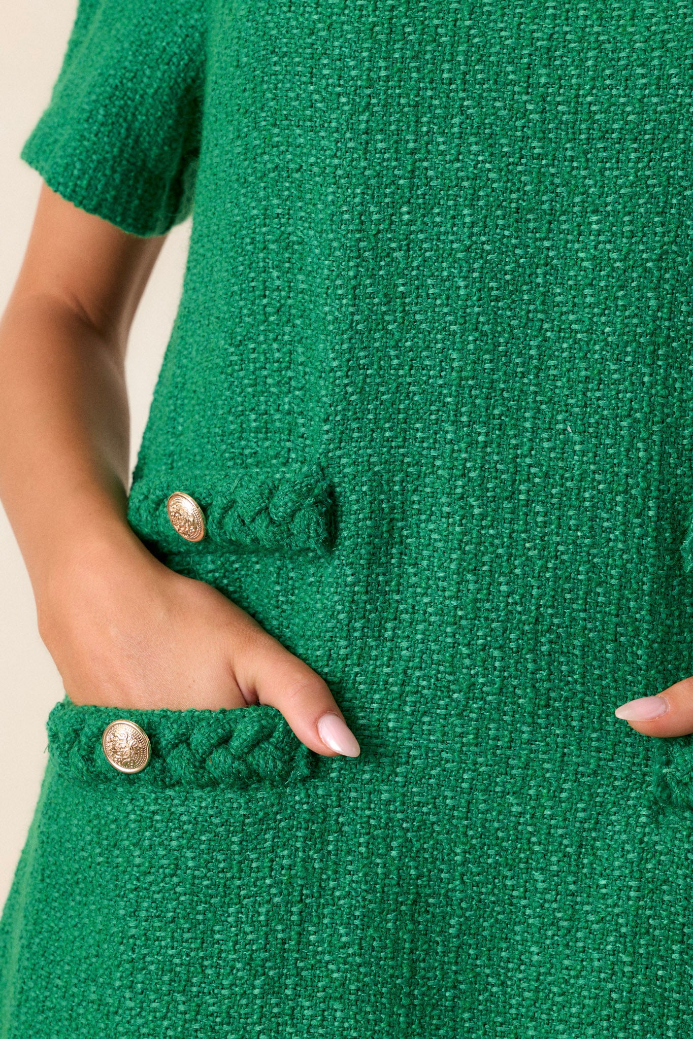 Close-up of the green mini dress focusing on the braided round neckline, gold accent buttons, and the texture of the tweed material.