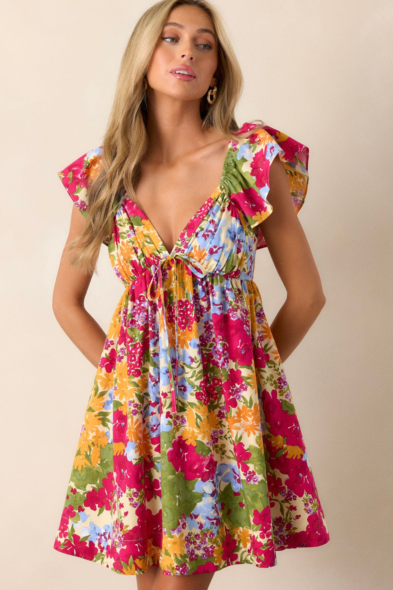 Front angled view of the floral dress featuring a smocked back with a functional zipper, two functional pockets, and ruffle sleeves