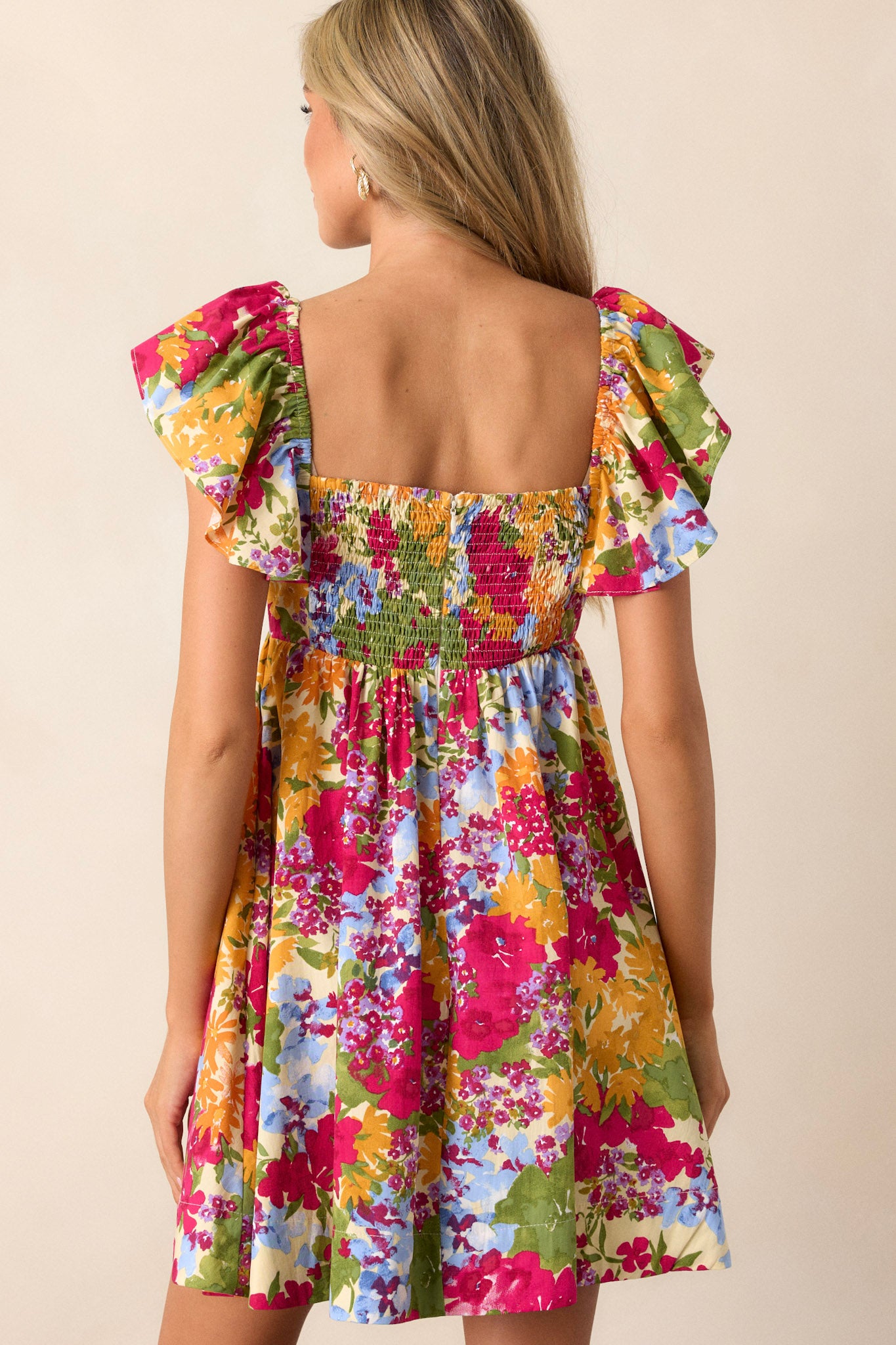 Back view of the floral dress highlighting the smocked back with a functional zipper and the flow of the fabric.