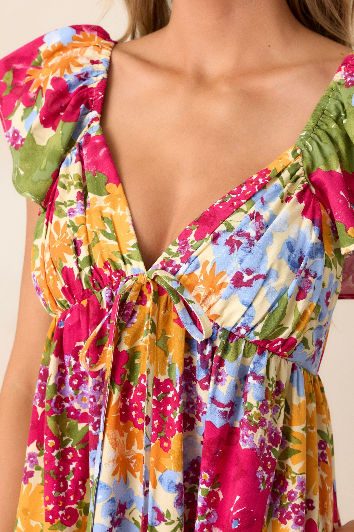 Close-up of the floral dress focusing on the smocked back, functional zipper, ruffle sleeves, and one of the functional pockets.