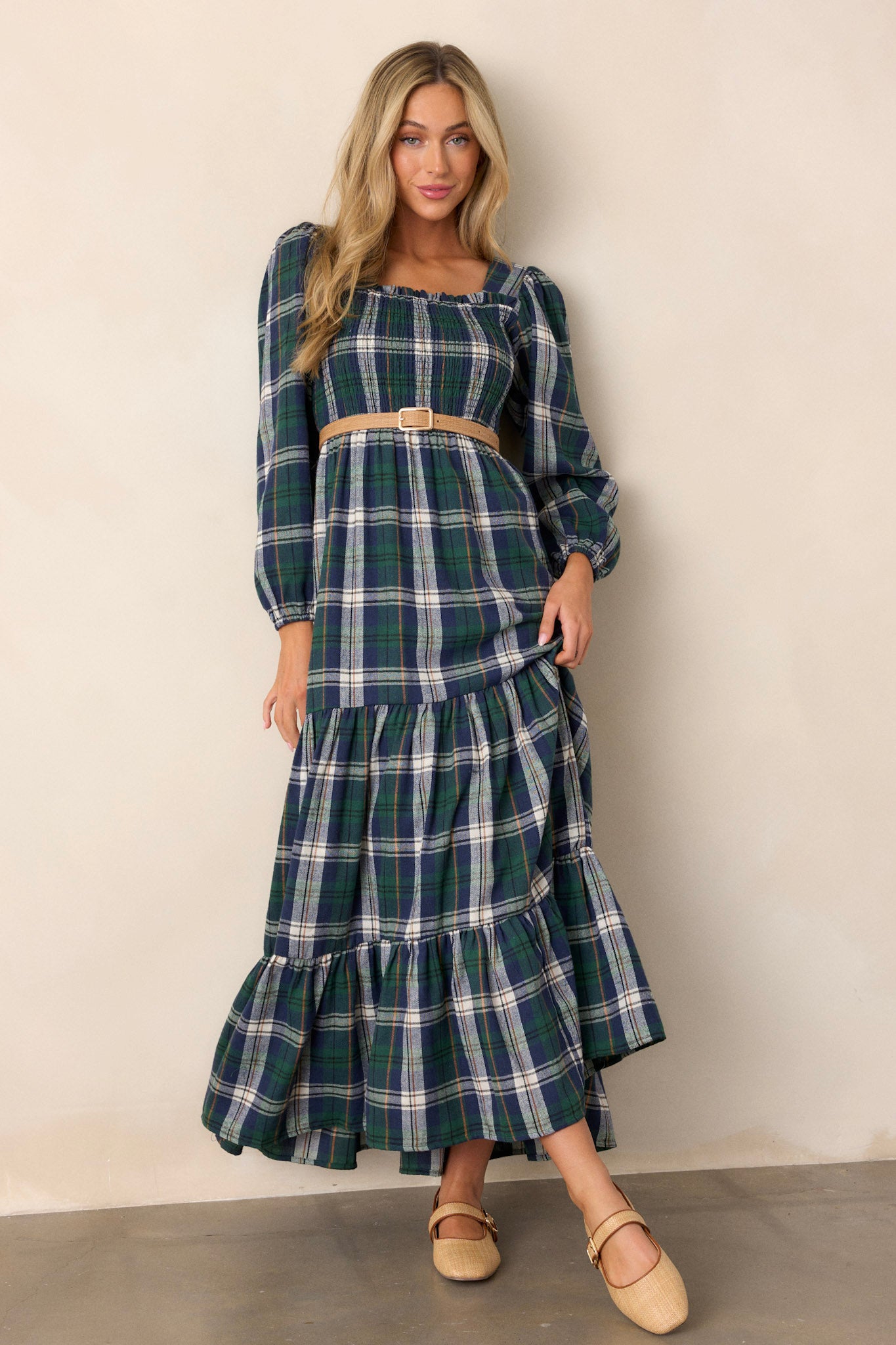 This dress features a square neckline, long sleeves with elastic cuffs, a fully smocked bust section, a self-tie belt at the waist, and a long, flowy skirt.