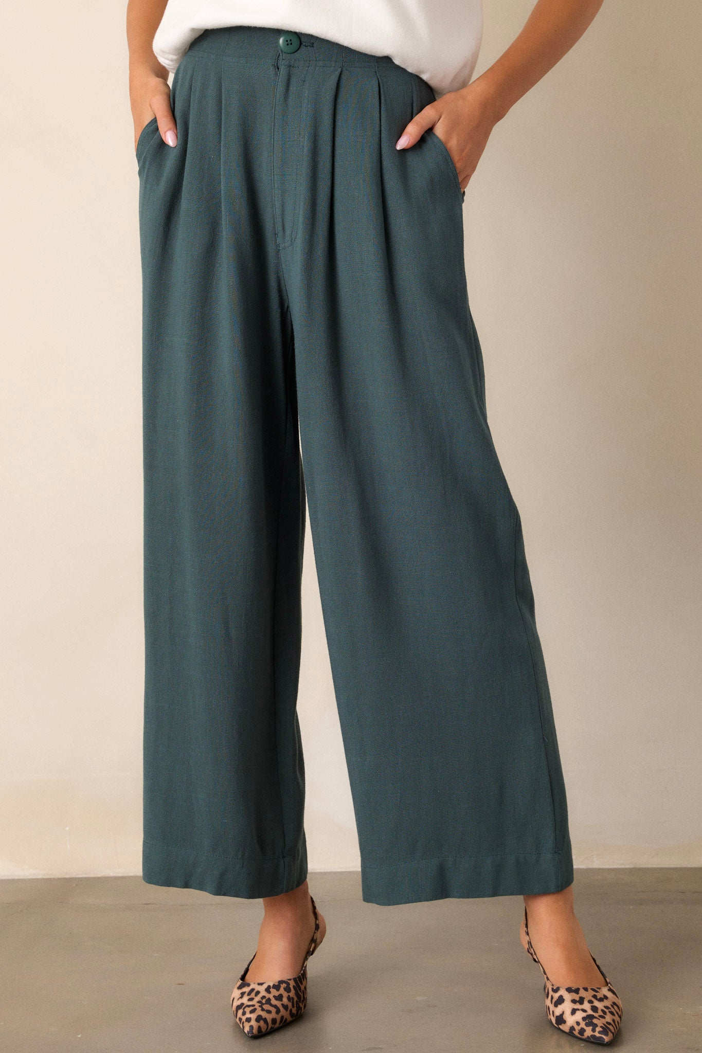 Front view of green pants featuring an elastic waist insert, a button zipper closure, functional hip pockets, and a straight leg design.