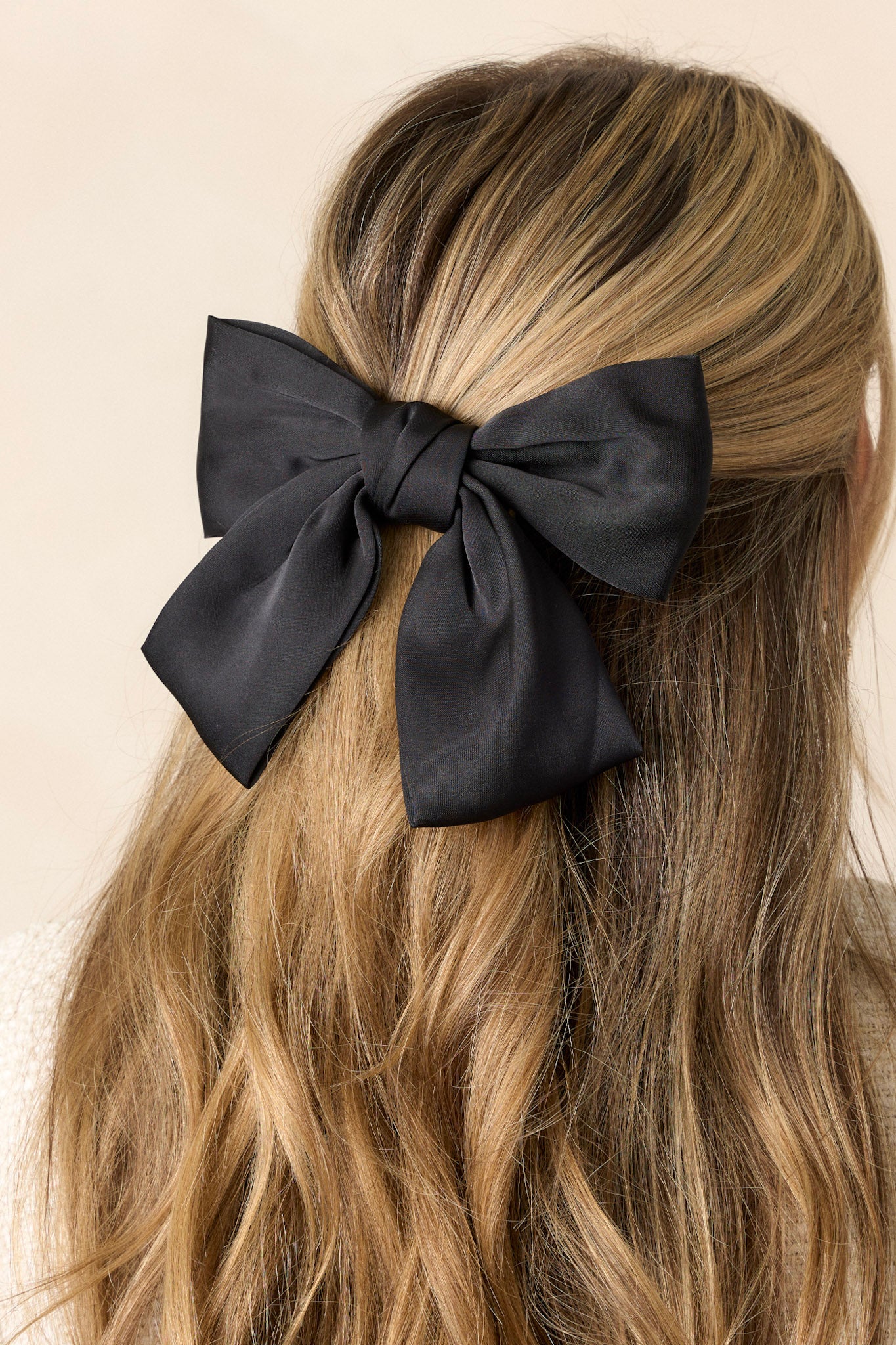 This hair clip features a classic black bow and a barrette clip.