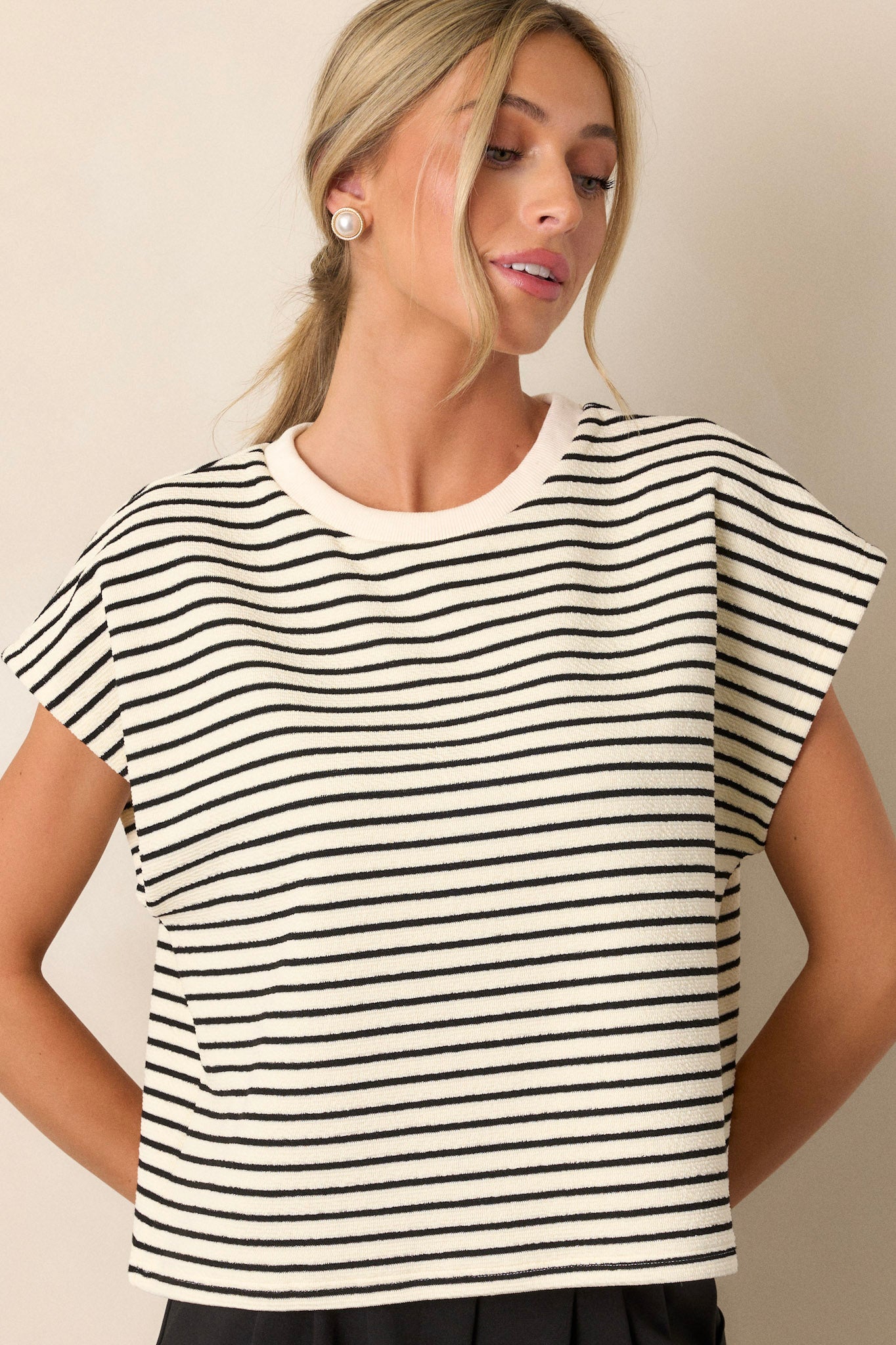 Front angled view of an ivory top featuring cap sleeves, a ribbed neckline, and a boxy fit