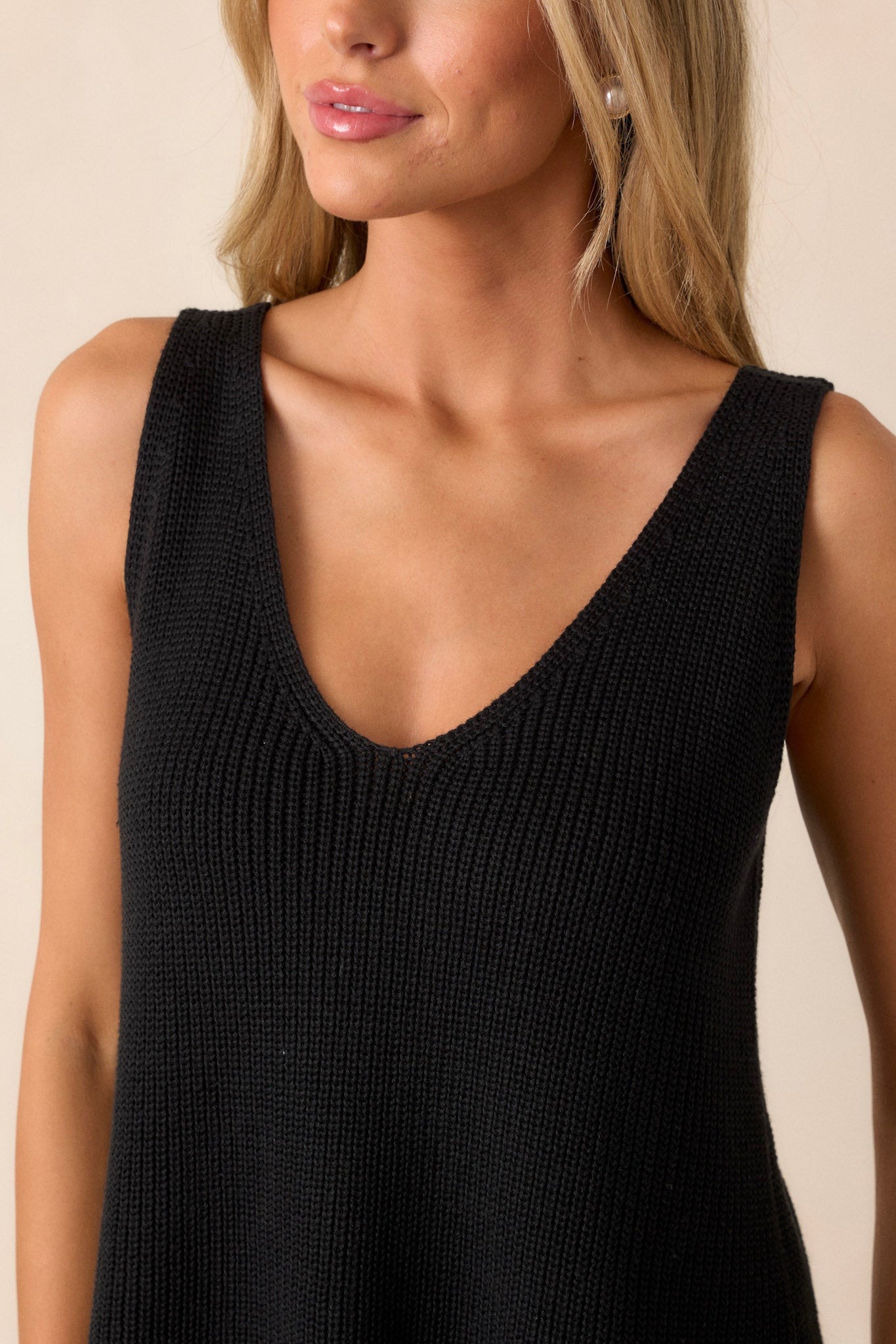 Close-up of the black knit tank top focusing on the soft knit material, v-neckline, and the free cut hem.