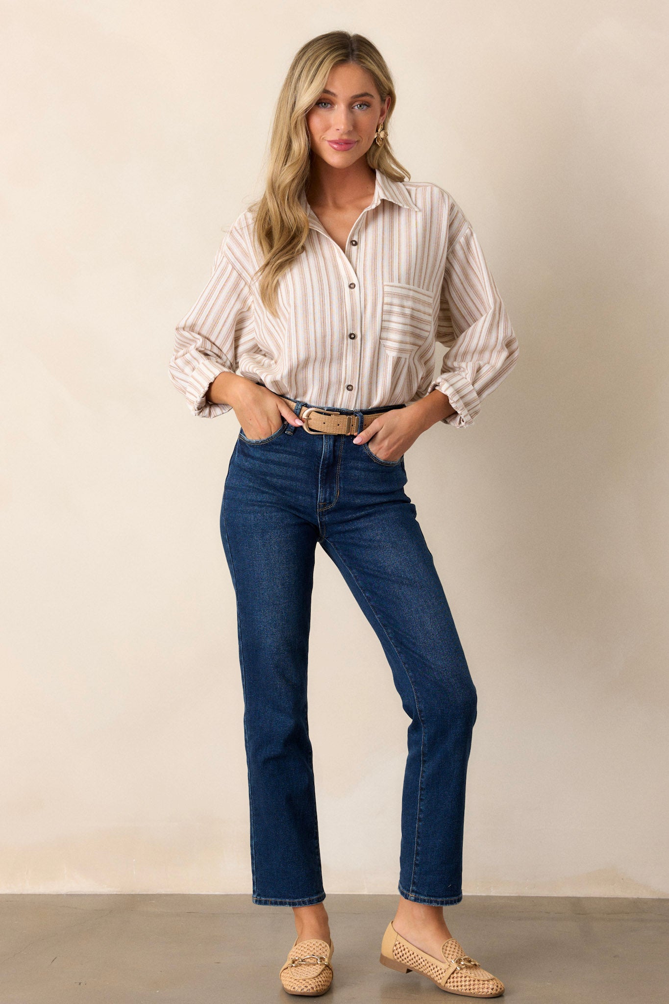 Full length view of dark wash jeans featuring a high waisted design, a button and zipper closure, functional front and back pockets, and a straight leg fit