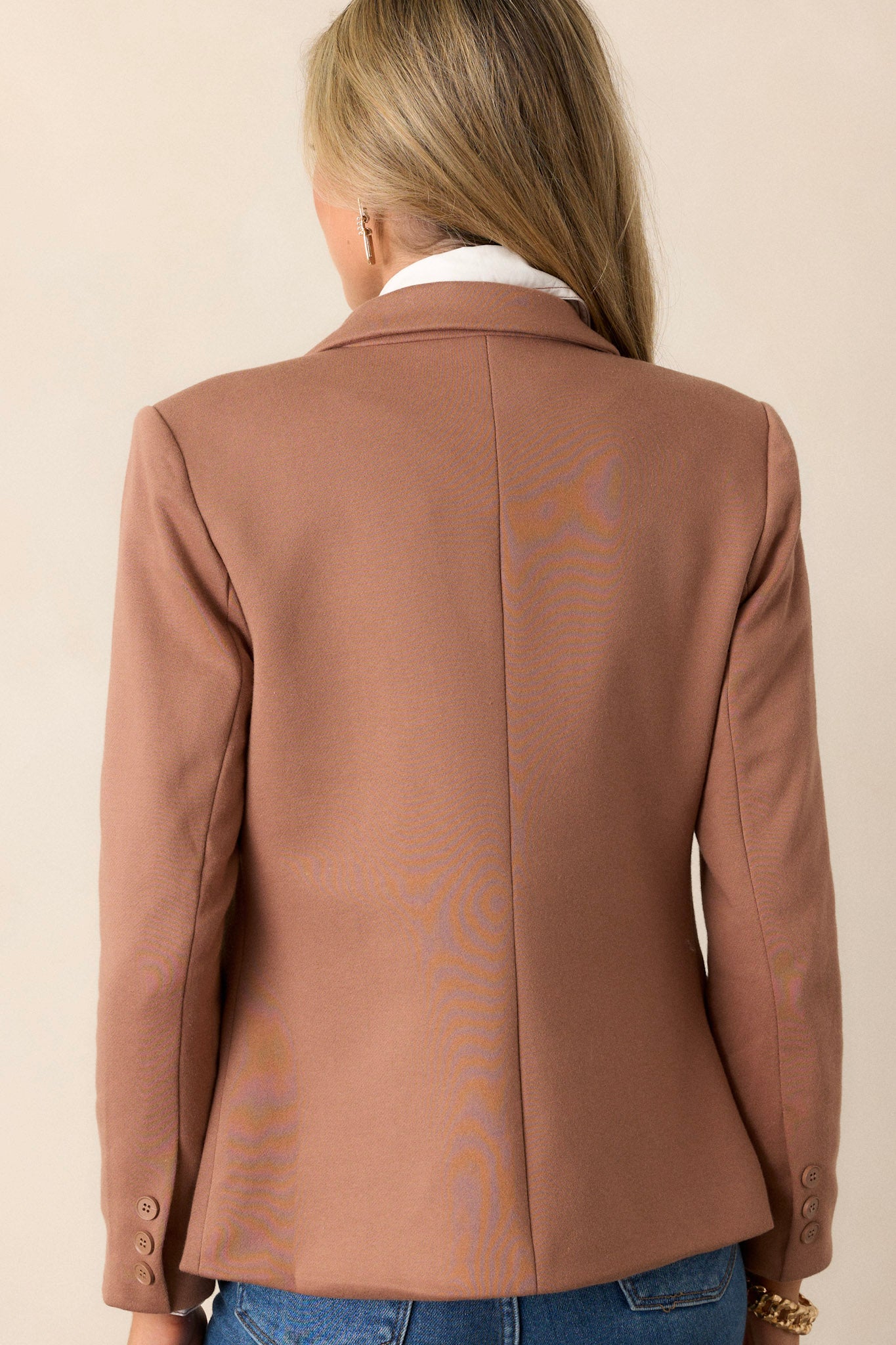 Back view of the tan blazer showcasing the clean lines and the overall structure, emphasizing the padded shoulders.