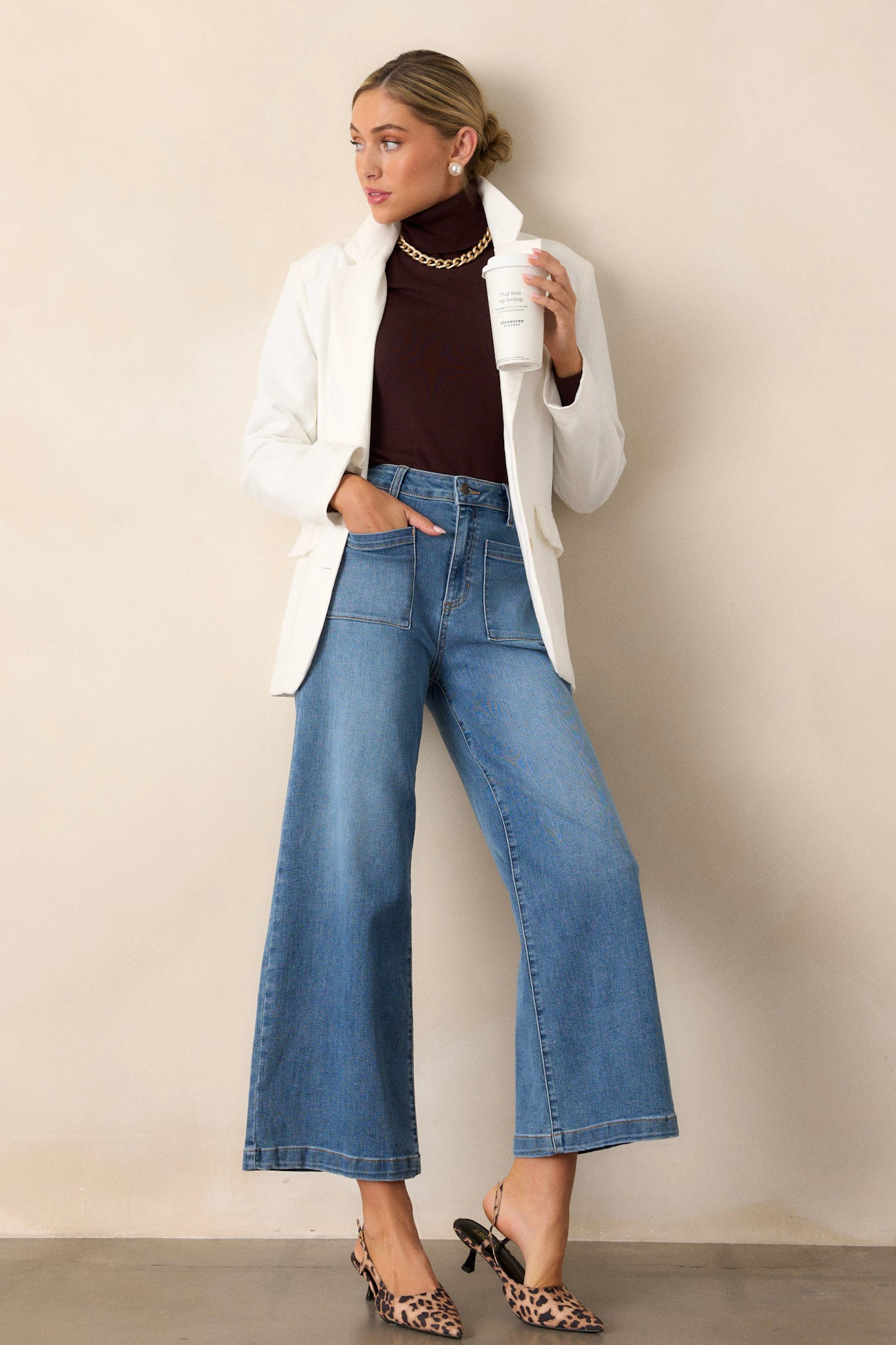 Front angled view of medium wash jeans featuring functional belt loops, a button zipper closure, functional pockets, and a wide leg design