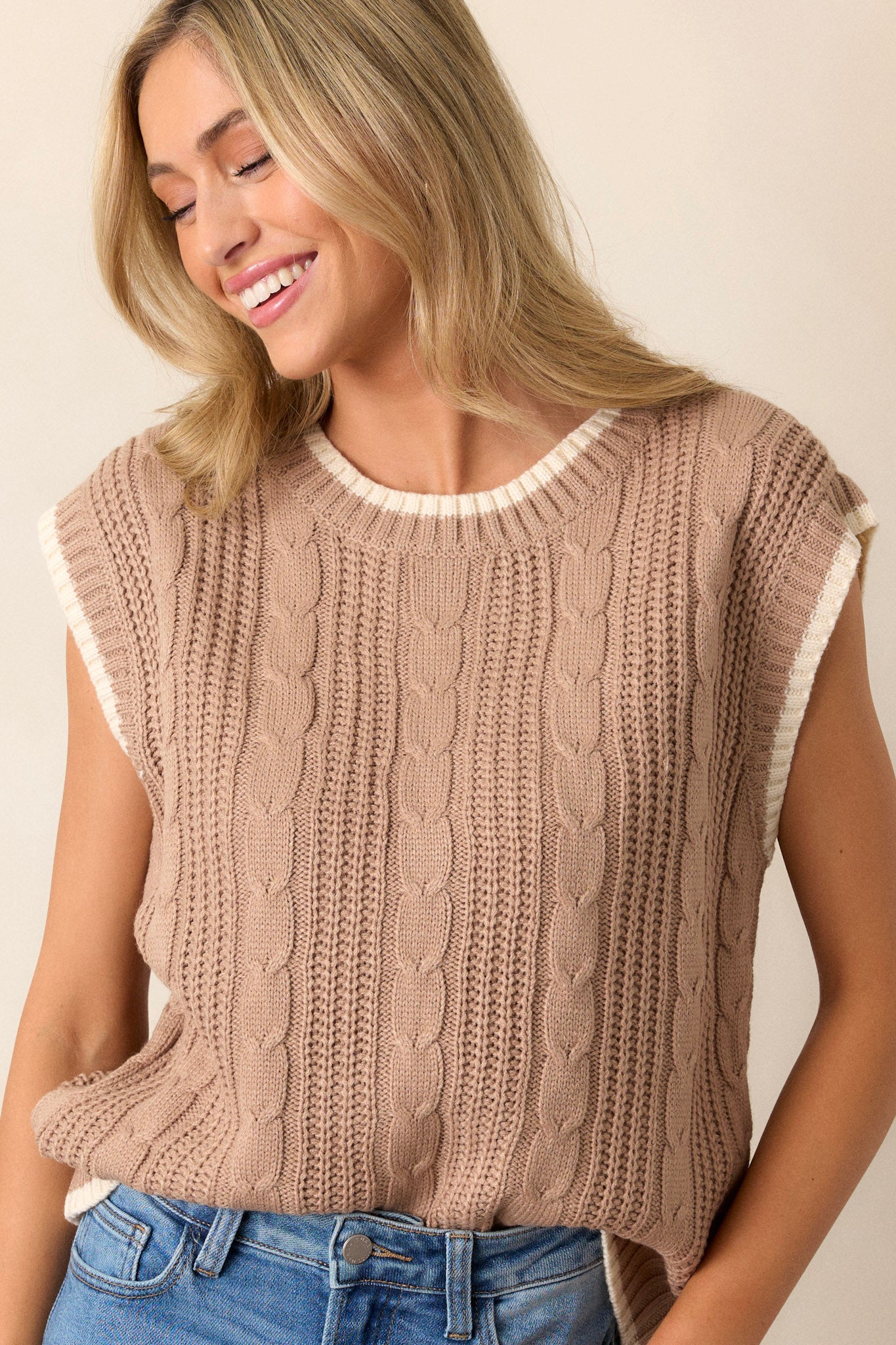 Front angled view of a knit sweater top featuring a high rounded neckline, a soft knit texture, cap sleeves, and an ivory trim